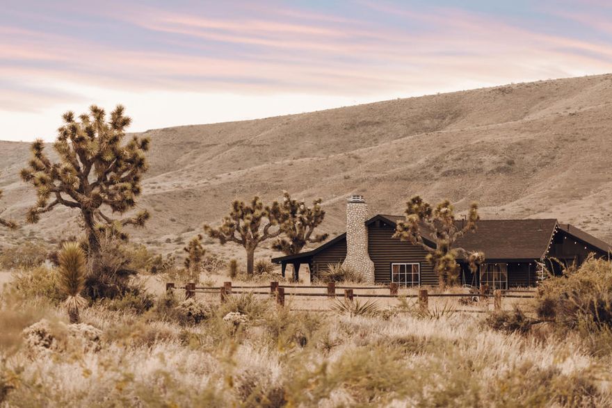 Now offered at $995,000, this is a rare opportunity to own a proven, income-producing retreat in one of the High Desert's most iconic locations. Over nearly four years of operation, the property has generated more than $505,000 in gross rental revenue across 390 bookings, demonstrating strong and sustained demand. The home maintains an approximate 59% occupancy rate, making it a compelling investment in a market with limited comparable inventory.Adding to its appeal, the property is situated within unique zoning that allows for flexible use, supporting its continued operation as a short-term rental while offering potential for creative or alternative uses (buyer to verify). This zoning distinction further differentiates the property from surrounding inventory.Welcome to The House of Roy, a celebrated Pioneertown desert escape set on nearly 1.27 acres, just three blocks from the legendary Pappy & Harriet's. This beautifully updated log cabin features 3 bedrooms plus an additional bedroom/sleeping loft and 3 bathrooms, highlighted by soaring 20-foot ceilings and a warm, rustic interior that blends authentic character with modern comfort.Surrounded by sweeping 360-degree mountain and desert views, the property captures the essence of High Desert living. Outdoor amenities include private porches, a hot tub, cowboy tub, hammock garden, and a former guest house converted into a speakeasy--ideal for entertaining and experience-driven short-term stays. A fully remodeled airstream is also included, providing additional guest accommodations or a creative studio.The owners have invested over $250,000 in recent improvements, including a remodeled kitchen, expanded living area, updated HVAC systems, electrical upgrades, new interior and exterior finishes, an outdoor deck, EV charging, and a fully remodeled airstream--enhancing comfort, efficiency, and long-term value.Already established as a successful short-term rental near Joshua Tree National Park, this property offers exceptional income potential alongside lifestyle appeal. Whether seeking a Pioneertown investment property, a High Desert vacation retreat, or a full-time residence, The House of Roy delivers a rare blend of character, performance, zoning flexibility, and location. Income and rental history available upon request.