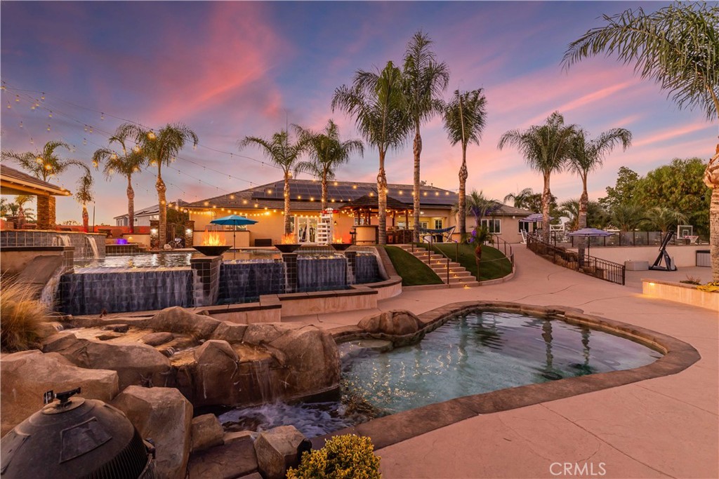Welcome to this entertainer’s dream estate in the exclusive gated community of Wynfield Estates, West Murrieta. Set on over 2 acres, this stunning single story home has been thoughtfully upgraded inside and out, offering a resort style lifestyle with every detail designed for comfort, beauty, and functionality. Step inside to find soaring ceilings, brand new hardwood floors, fresh paint, crown molding, modern light fixtures, and barn door accents. The remodeled chef’s kitchen is a showpiece, featuring Wolf & Sub Zero appliances, double ovens, a massive island, new cabinetry, walk in pantry, and designer lighting. Spacious living areas include multiple fireplaces, a huge family room with surround sound, and an office with custom built ins. The primary suite is a retreat with dual walk in closets, a fireplace, smart window coverings, and mountain views. Designed for unforgettable gatherings, the backyard rivals a luxury resort. Highlights include two pools with Baja shelf, two story water slide, cabana bar with palapa roof, fire pits, putting green, football style lawn, basketball court, children’s playground, and outdoor theater. An advanced Luxor smart lighting system, rock speakers, whole house audio, and outdoor TVs create the perfect atmosphere for both relaxation and entertaining. Additional upgrades include a new pool heater, reclaimed water irrigation system, epoxy floored 4 car climate controlled garage, Tesla charger and Tesla gateway, water softening system, newer garage doors, commercial window tinting, multiple fruit trees, rose gardens, and RV parking. Energy efficiency is built in with a leased solar system & the property also offers a 4-stage whole house water filtration system, water softener, and reverse osmosis system for pure drinking water. This rare estate seamlessly blends modern upgrades with timeless charm, offering space, privacy, and unmatched amenities all within minutes of shopping, dining, wine country, and top rated Murrieta schools. Truly one of the most extraordinary properties on the market today. More photos coming tomorrow!