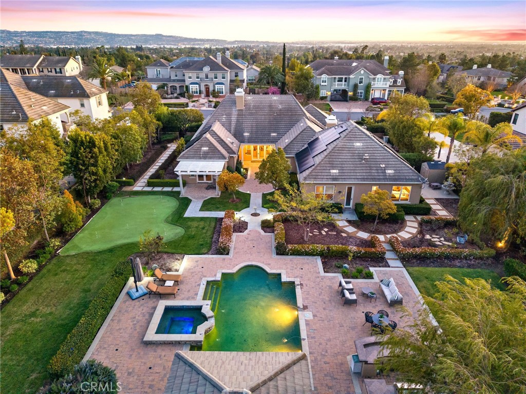 Your quest for the ideal blend of sprawling single level luxury, location and room to grow will be rewarded at the exclusive gated community of Manor House in Yorba Linda, where this turnkey estate presents everything on your wish list. A circular driveway, custom fountain and gated motor court complement the residence’s distinctive architecture, which is highlighted by an arched entry door. Adorned with custom crown and base moldings that continue throughout, handsome columns and sweeping archways, a formal foyer provides an appropriately impressive introduction to the home and resort-style back yard. An office with interior French doors and a formal dining room flank the foyer, and a formal living room with fireplace, custom built-in cabinetry, and French doors opening to a covered patio is perfect for upscale entertaining. The generously proportioned floorplan continues to a fireplace-warmed family room with surround sound and a wood-paneled wall with built-ins. Sought-after refinements are showcased in an island kitchen with granite countertops, full backsplash, stained wood cabinetry with glass uppers, a nook, and a butler’s pantry with wine storage and an under-cabinet beverage refrigerator. Chefs will appreciate a suite of preferred stainless steel appliances that includes a built-in refrigerator, double oven and a six-burner cooktop with griddle. An ideal study room/den with built-in desk is located just off the kitchen, and an attached garage accommodates 4 vehicles. Four spacious bedrooms and 4.5 baths provide comfort for residents and guests, with select secondary bedrooms offering ensuite baths. The primary suite is an elegant escape complete with an entry vestibule, covered patio, sitting area, fireplace, built-in entertainment cabinetry, jetted tub, separate vanities and a walk-in closet with custom built-ins. Tray ceilings with designer paint, custom draperies and plantation shutters, solar power, a Ring video doorbell, and hardwood, designer tile and patterned-carpet flooring give the home an air of sophisticated style. With a flat lot of approx. 39,000 square feet, park-like grounds with no home behind embrace the residence with manicured hedges, paver-finished patios, fountains, a rose garden and a putting green. Entertaining is elevated with a five-star pebble-finished pool and spa with water features, a built-in BBQ bar, and a cabana with fireplace and TV. Seller owned Solar. Near schools, golf, shopping, parks, and trails