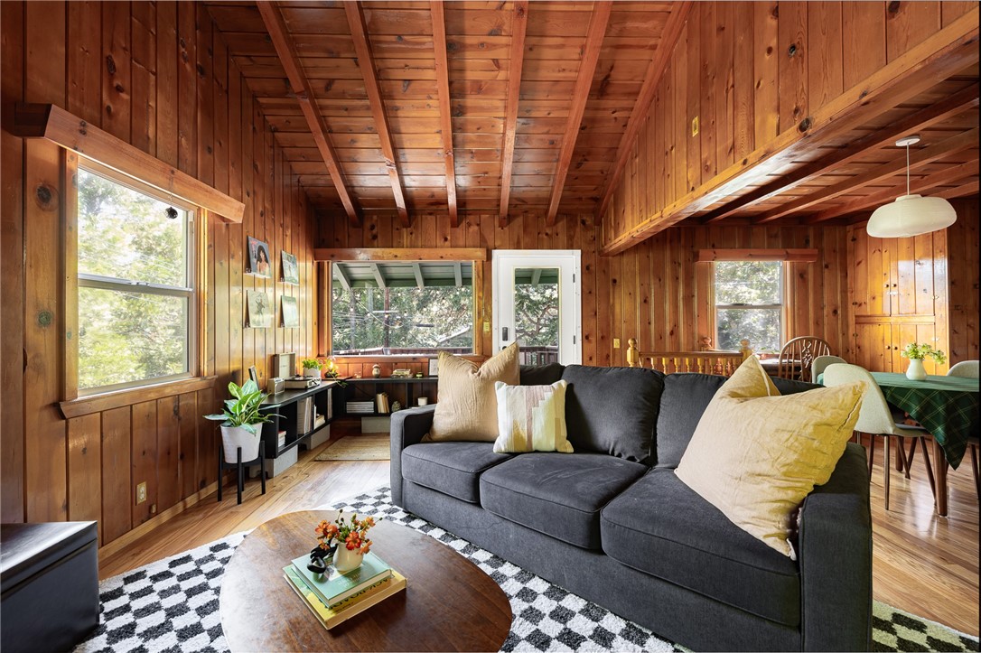 A dream 1940s cabin in the woods!
Tucked away behind lush, green landscaping that offers both privacy and plenty of natural light, this enchanting cabin is the perfect retreat. Step through the front door into a cozy kitchen featuring freshly painted cabinets, a charming vintage-inspired fridge, and a sweet built-in breakfast nook—ideal for enjoying morning coffee and a good book. Gorgeous wood paneling and hardwood floors run throughout, adding warmth and character. The open-concept living and dining space is centered around a stunning brick fireplace. A sunny corner with a large picture window—currently used as a music nook—adds charm, while another well-lit workspace with a desk makes working from home a joy. The spacious bedroom offers ample storage and is conveniently located next to the vintage-style bathroom. Step out from the living room onto a large wood deck—perfect for lounging, entertaining, or gathering around the fire-pit on cool evenings. The backyard also has room to add an additional parking space if desired. Downstairs, a versatile bonus space with its own private entrance and patio presents an exciting opportunity—ideal for guests, a home studio, or even a rental investment. This lower level also includes a half bath and laundry area. This cabin is full of character, functionality, and potential—come see it for yourself!