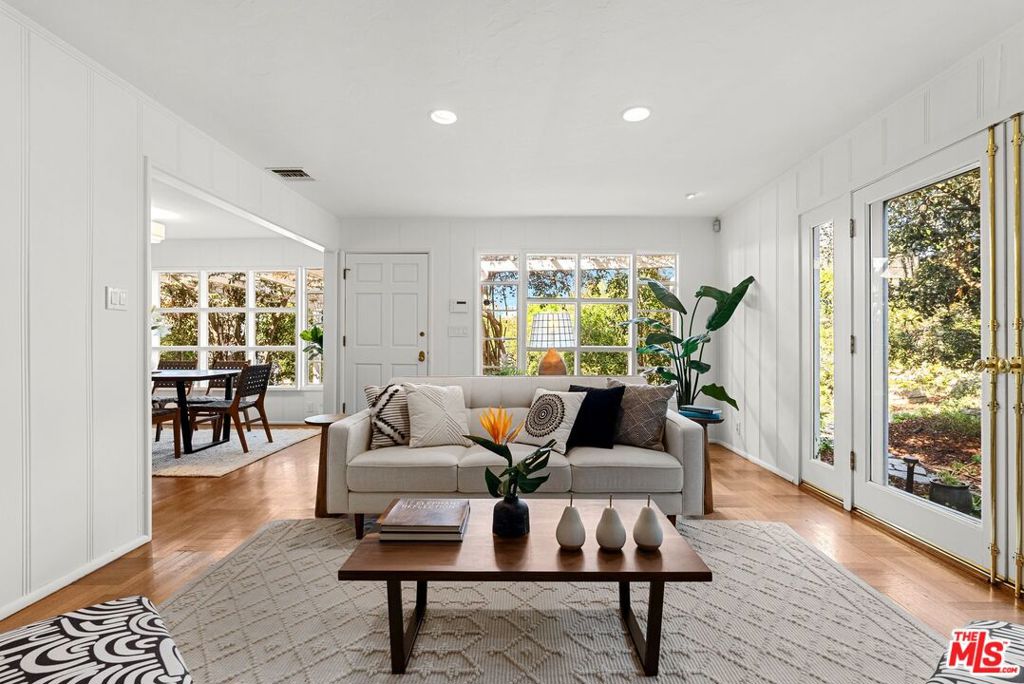 Nestled in the heart of the Hollywood Hills, this enchanting storybook cottage offers a unique blend of original charm and modern comfort. Ideally located just moments from the Runyon Canyon trailhead, the property boasts over a quarter of an acre, providing unmatched privacy and tranquility while still being close to the excitement of the city. With original wood accents and plentiful natural light, the open floor plan is perfect for entertaining. Hardwood floors flow seamlessly throughout, adding warmth and character to each room. The spacious living room features a central fireplace with a brick hearth and French doors that lead to one of several outdoor patios. The bright and airy dining room opens into the kitchen with a beautiful vintage range, stainless steel appliances, and a cozy breakfast nook. Plentiful closet space in the hallways, along with a laundry room/pantry adjacent to the kitchen, add to the convenience of modern living. The expansive primary bedroom serves as a serene retreat, complete with a work-from-home office space or reading lounge. This peaceful room opens to an additional covered patio in the back. A secondary bedroom is ideal for guests or children, while a full bathroom in between features vintage terracotta tile floors and countertops. The outdoor space of this property is an oasis, surrounded by lush landscaping on all sides with numerous areas for relaxation, entertaining, and gardening. The patio along the front of the house, shaded by a wood canopy, is perfectly positioned for enjoying sunset alfresco dining during warm summer evenings. This rare gem in the Hollywood Hills combines the charm of yesteryear with the comforts of today, all while offering an unparalleled sense of privacy and a prime location.