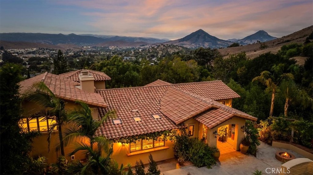 Your Spanish oasis beckons! As you enter the garden gates of this one-of-a-kind villa, a lush private courtyard with water fountain greets you. This is an excellent space for entertaining, with koi pond, gentle water wall, gas firepit, and lush green foliage on the banks of the year-round creek (Blue Line; with water rights). All of this is a refreshing introduction to the iconic Spanish style home with approximately 3,935 square feet of flexible living space. Four bedrooms (1 set up as an office) and 3 1/2 baths. Enter into an elegant foyer which welcomes you in the heart of the home: The great room with a fireplace at either end, polished wood flooring, outdoor veranda, sitting nook, large dining area, amazing kitchen, all offering views over the city and surrounding hills. One flight up is the primary retreat with large southwest facing deck, corner fireplace, and elegant ensuite bathroom. Heading downstairs from the primary suite you'll find two more bedrooms, a library nook, full bath, and hardwood floors. These bedrooms have beautiful views to the west. Moving down a few more stairs brings you to the wine cellar and family room area with another bedroom and full bathroom. This area would make an excellent guest suite. There are two large double garages accessible from the house, with a combined garage space of 1,176 sq. ft. The separate guest house is also accessed off the main courtyard; featuring one bedroom, one full bath, kitchen, and living room. This space totals 624 sq. ft. A lovely deck provides relaxation, enhanced by the sound of the adjacent creek. Fenced yard areas on the lower part of the lot for pets, gardens, etc. Adjacent and undeveloped 3 acre parcel is also available for purchase separately.