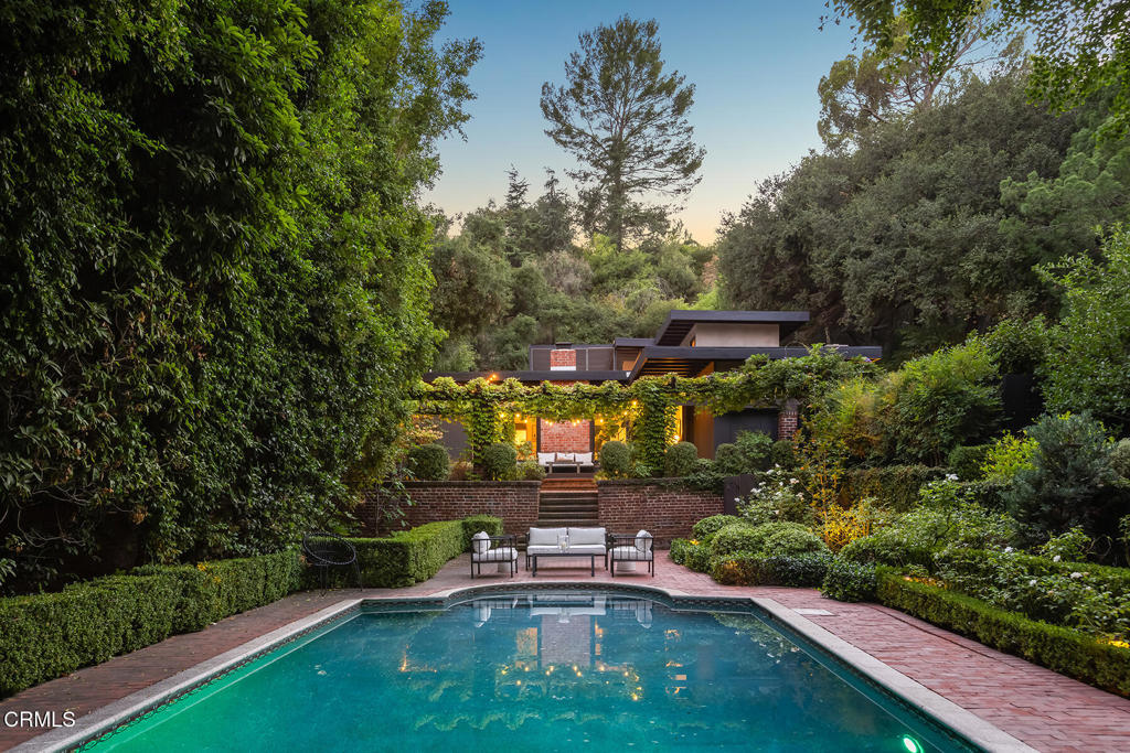Set in Pasadena's coveted Linda Vista neighborhood, just moments from the Rose Bowl and the city's cultural heart, this rare architectural residence offers a lifestyle of timeless modern luxury. Commissioned in 1955 by celebrated illustrator Harry O. Diamond and designed by Thomas Matthias, the home is a striking example of mid-century, defined by clean lines, dramatic walls of glass, and an effortless connection to nature. This home has been noted and featured twice in Sunset Magazine for its architectural design and estate style gardens. In true Mid Century design, high-beamed ceilings and walls of glass open to views of the sparkling pool and lushly landscaped gardens, blurring the line between indoors and out. The lush mature landscaping frames the pool while the water reflects the dappled sunlight filtering through the trees. The grounds offer unparalleled elegance and privacy with a manicured yard, a vine draped pergola, abundant fruit trees, and multiple outdoor sitting areas, creating a sublime setting for refined entertaining and peaceful retreat. At its core, a breathtaking two-story enclosed atrium anchors the residence serving as a lightwell and providing a serene focal point for common areas and daily living spaces; a rare architectural statement in mid-century design.The home balances sophistication and comfort. The upstairs primary suite is a private sanctuary, with expansive glass walls and a balcony overlooking the central atrium. A spacious downstairs suite with vaulted ceilings, clerestory windows that invite natural light, and an expansive walk-in closet serves as an ideal retreat or second primary bedroom. Two additional bedrooms offer refined flexibility, easily serving as guest suites, private offices, or personalized retreats. The kitchen features an open layout that seamlessly connects the family, dining, and living areas, creating a harmonious flow that results in openness and balance. This home is an opportunity for collectors of design and architecture. Situated in one of Pasadena's most desirable enclaves, the Harry O. Diamond Residence reflects architectural pedigree, timeless modern design and a piece of California's rich artistic legacy.
