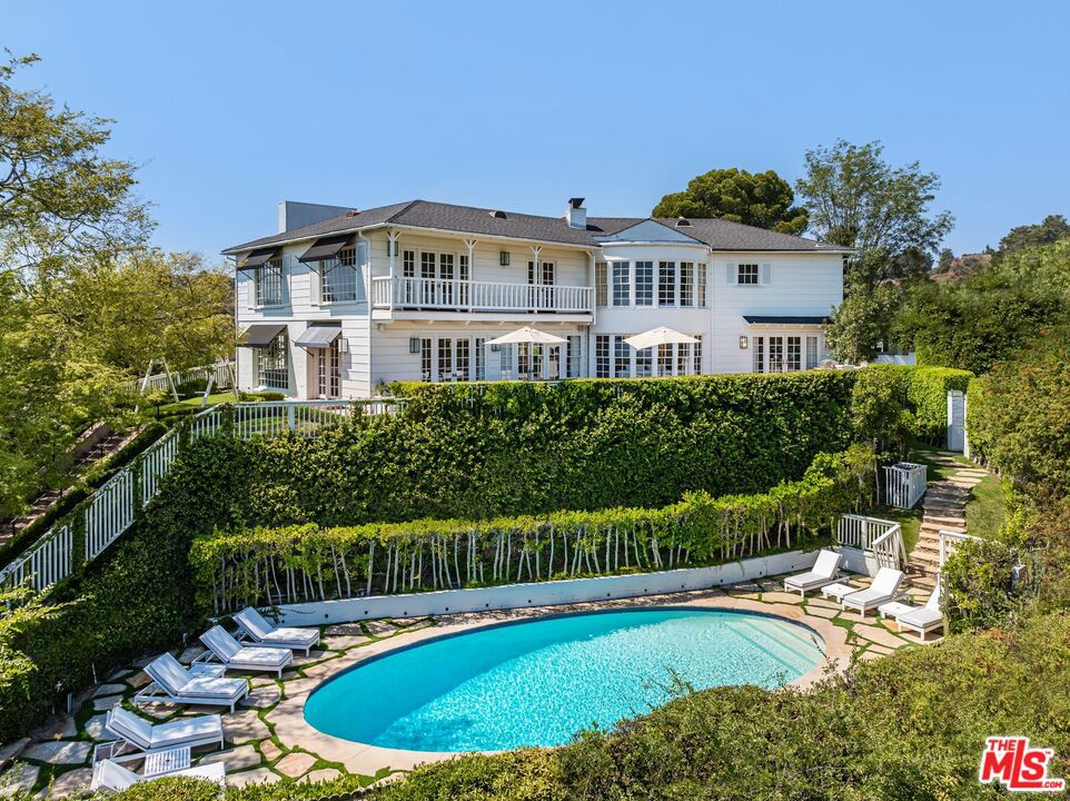 At the crest of the mountain, where city lights dissolve into the endless ocean, rises a South Hampton inspired Georgian Estate. Inside, soaring ceilings and walls of French doors flood every room with natural light, while rich dark hardwood floors ground the interiors in timeless elegance. The primary suite commands its own private wing, a sanctuary of serenity, while four guest suites and six bespoke bathrooms offer comfort and privacy for family and friends. At the heart of the home, a chef's kitchen flows seamlessly into a family room, an entertainer's dream designed for both intimate evenings and grand gatherings. Four dramatic fireplaces lend warmth throughout. Beyond the residence, manicured gardens frame a sparkling resort-style pool, and expansive terraces provide multiple settings for alfresco dining, sunset cocktails, and quiet reflection. This is more than a home, it is a legacy estate, crafted with impeccable provenance and positioned to capture the most breathtaking views of both city and sea. A once-in-a-lifetime opportunity to own a residence destined to be treasured for generations.