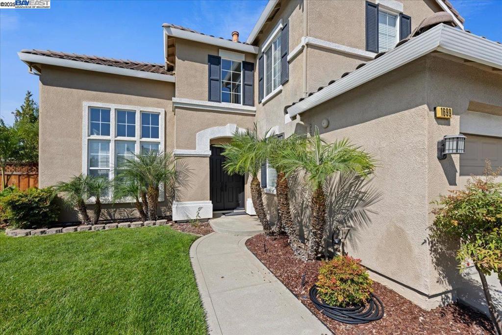 1699 Lodestone Rd, a stunning home located in the highly desirable Sandhurst development. You'll be captivated by the soaring vaulted ceilings and abundance of natural light. The heart of the home is the exquisite, remodeled kitchen, boasting a distinctive Quartzsite waterfall island, quartz countertops and top-tier Café appliances, including an internet-enabled oven and a premium EroCave wine refrigerator that can accommodate up to 100 bottles. Through the double French sliders, find a backyard paradise with a Travertine patio equipped with an outdoor kitchen, fireplace, surrounded by palms, fruit trees, and lush foliage. The functional layout includes a spacious first-floor bedroom and bath, ideal for guests or a home office and a conveniently located laundry area with a utility sink and storage. Upstairs, the primary suite offers a luxurious bath with soaking tub, walk-in shower, and a extraordinarily spacious walk-through closet. Additional features include new dual HVAC units, new water heater, dual-pane windows, fresh interior paint, LVT flooring and a 3-car garage. Situated on a prime corner lot, this property is just moments away from the south bay corridor and is served by top-ranked Livermore schools. This residence offers the perfect blend of luxury and convenience.