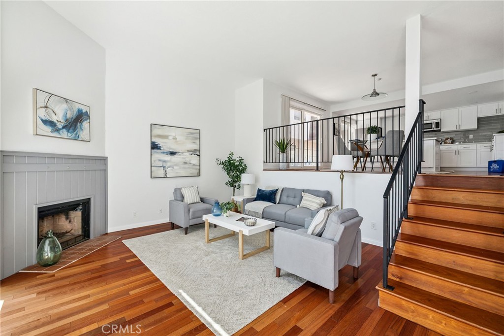 This EXECPTIONAL home truly has it all, ideally located STEPS TO the BEACH, shopping, and more! This delightful END UNIT townhome boasts a west-facing direction that allows for abundant natural light. It features an expansive front porch, perfect for showcasing your gardening talents or adorning beach style decor, a large attached 2-car garage with washer and dryer hookups and is within walking distance to the beach, restaurants, shops, and a mere stroll to Redondo High School. This home has been beautifully REMODLED throughout, featuring fresh paint and newer carpets. It includes 3 spacious bedrooms upstairs, with the primary bedroom and en suite bathroom with double sinks, a soaking tub, and separate shower. Each bedroom has abundant closet space. A skylight on the staircase brightens the area, contributing to the home's cheerful atmosphere. Additionally, there is a large 4th bedroom downstairs, providing great privacy. The kitchen showcases a stunning quartz countertop island with soft close cabinets, beautiful modern backsplash, and stainless-steel appliances, and recessed lights. The dining room with gleaming hardwood floors and OPEN FLOOR PLAN is ideal with a spacious balcony conveniently adjacent to the kitchen making it perfect for barbecues or simply enjoying the refreshing ocean breezes while unwinding.
The living room also showcases gleaming hardwood floors and offers an updated fireplace that adds ambiance, creating an inviting space ideal for reading or entertaining. With an impressive walkability score of 93, this home is considered a "Walker's Paradise" in a highly sought-after neighborhood! *** Property is also for sale***