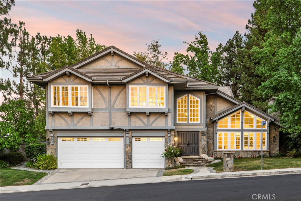 Perched high in one of Woodland Hills’ most sought-after neighborhoods, Valley Circle Estates, this stunning residence at 6032 County Oak Rd offers the perfect blend of luxury, comfort, and smart home convenience. From the moment you step inside, you’re welcomed by grand scale— soaring vaulted ceilings, a dramatic curved staircase leading up to 3 of the 4 bedrooms, and a grand foyer that sets the tone for the home’s elegant yet functional layout. The thoughtful floor plan provides great flow between all main living spaces. One side leads to a main-level ensuite bedroom, perfect for guests or a home office, while the other opens to a spacious great room with a breathtaking wall of windows and French doors that fill the home with natural light. At the heart of the home is a TRUE chef’s kitchen, ideally located between the formal dining room and family room. It features a double Thermador oven, Viking range and hood, huge Thermador refrigerator, walk-in pantry, a double-sided island with prep sink, and a breakfast nook that leads out onto the beautifully landscaped yard. Step outside and you’ll find an entertainer’s dream. A full-length patio stretches across the back of the home, with access from the dining room, kitchen, and family room. The brand new built-in BBQ with a direct gas line makes outdoor cooking easy, while the expansive covered seating area is perfect for hosting year-round. A smart heated pool with a waterfall, new hot tub, and expansive flat lawn framed by mature trees create a private backyard oasis. Upstairs, the oversized primary suite features partial valley views from its private balcony, along with a luxurious ensuite bath that includes a floating tub, walk-in shower, dual vanities, and a gallery style walk-in closet. Two additional bedrooms and a well appointed full bathroom complete the upper level. Additional enhancements include a fully upgraded three-car garage with new doors, openers, custom built-in storage, and its own AC and heater unit. Integrated laundry and mudroom situated just off the garage, providing a practical entry point into the home. The home is fully equipped with smart home technology throughout, including smart thermostats on both floors, integrated lighting, locks, security cameras, and an ADT security system—fully compatible with both Alexa and Google. For added peace of mind, the community offers 24/7 security patrols. A rare opportunity to own an elevated, move in ready home in a prestigious neighborhood.