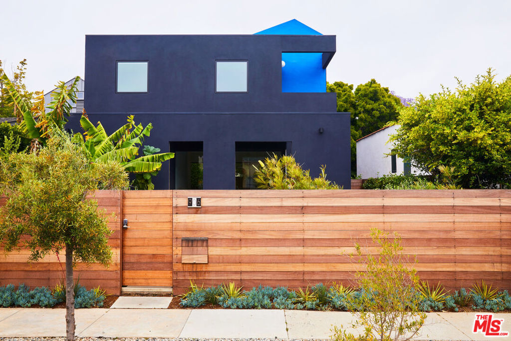 Playing with color and light, the "House within a house " designed by Barbara Bestor of Bestor Architecture, is vibrant and spirited and ideally situated in the heart of the Venice Walk Street neighborhood. A pop of bright blue contrasts with the serene navy, drawing your eye up to an illusion of a house upon and inside a house. The front patio is an open-air extension of the living area, yet retains a sense of privacy with a library nook and shaded family room. This enclosed patio emphasizes indoor-outdoor living and shades a glass-walled living room. Inside, an open floor plan deftly separates key areas, including a corner library with a cedar-sided wall that opens onto the front patio. An oak-clad stairwell divides the library from the dining area, which in turn opens to an outdoor deck at the rear of the property. Stepping down into a lush yard, an outdoor shower awaits. Upstairs, there are three bedrooms and two bathrooms, each with a balcony. "It's meant to be a little reticent- not the biggest baddest box on the block" - Bestor