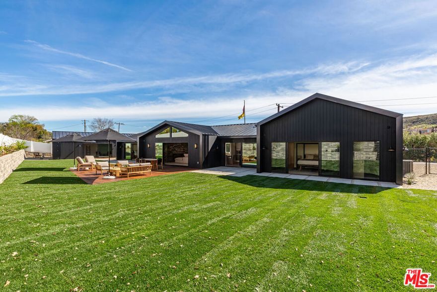 This is the house - your dream home, finally within reach. A masterpiece of design, completely reimagined by visionary Designer Tiaan Schreuder and expertly crafted by Ross Builders, this Old Agoura estate is where Mid-Century Modern elegance meets Scandinavian simplicity, creating the ultimate luxury coastal ranch lifestyle.  From the moment you step inside, soaring 14-foot vaulted ceilings with rift white oak beams draw you into an expansive, open living space - perfectly designed for both grand entertaining and effortless relaxation. The bar and gourmet Thermador-equipped kitchen set the stage for unforgettable gatherings, while wide-plank White Oak floors guide you through the home's spacious bedroom suites, each with custom spa-like baths. In the main bedroom suite, a full-size concrete soaking tub becomes the centerpiece of your private retreat, offering a serene space to unwind in ultimate luxury.  Every detail has been meticulously considered, from the floor to ceiling White Oak built-ins offering storage beyond your dreams - to the full-size dog shower, because even your furry friends deserve luxury. Step outside to a massive Ipe hardwood dining and relaxation area, set amongst flat, sprawling lawns leading to your private wellness retreat, complete with a Clear Cedar sauna, workout spaces, and more.  With four garage spaces and room for a dozen more cars, this property doesn't just check all the boxes - it sets the new standard. This isn't just a house; it's the one. Are you ready to call it home?