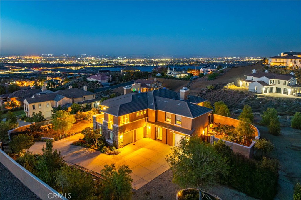 ***LIVE BEAUTIFULLY*** Nestled in the scenic foothills of West Palmdale, this exceptional 6-bed, 6-bath estate offers nearly 4,600 square feet of refined living space and showcases breathtaking panoramic views of the mountains, city lights, and tranquil lake. Designed with luxury and durability in mind, the property is fully gated with a custom entry and enclosed by a fire-hardened block wall with stone pillars—meeting LA County fire inspection standards and enhanced by a fire hydrant conveniently located at the property line. Inside, the home blends sophisticated finishes with thoughtful upgrades. The expansive kitchen is a true chef’s dream, featuring a GE Monogram appliance suite including a 36” induction cooktop, convection oven, and Advantium speed oven, along with dual sinks, dual dishwashers—including a Miele “knock to open”—a pot filler, under-cabinet lighting, and a massive 5' x 9' island topped with luxurious Caesarstone Statuario Nuvo. The adjacent formal dining room is illuminated by a modern chandelier and framed by motorized cellular blinds, while the spacious living room opens to the backyard through premium Marvin French doors. Throughout the main level, bamboo flooring with upgraded underlayment ensures comfort, insulation, and a clean, contemporary aesthetic. The 2 downstair suites are perfect for visitors or multigenerational living. Upstairs, the expansive primary suite is a spa-like escape, featuring dual custom vanities with quartz countertops and built-in power strips, lighted anti-fog mirrors, a soaking tub, and a glass-enclosed shower wrapped in Livorno Veincut Capri tile with marble penny tile flooring. Additional bedrooms offer unique design elements including floating vanities, LED backlit mirrors, solar or blackout shades, ceiling fans, and upgraded fixtures from Delta, Moen, and Hansgrohe. Outdoors, the estate continues to impress with mature trees, fruit-bearing lemon and lime trees, block and capped planters, a custom side gate, and an enclosed outdoor dining garden with custom metalwork. With high-end finishes, cutting-edge appliances, designer touches throughout, and a prime location in one of Palmdale’s most desirable areas, this estate offers an unmatched combination of elegance, privacy, and panoramic beauty. A rare opportunity to own a true hillside sanctuary.