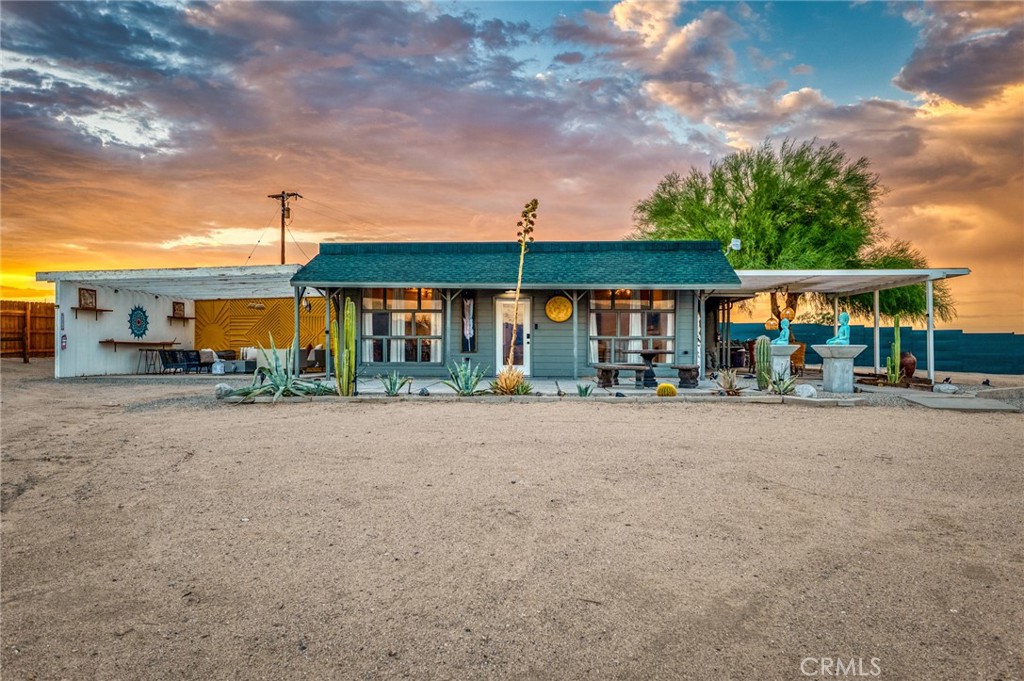 Welcome to this stylish 3-bedroom, 1-bath mid-century desert compound with 1,418 sq ft of living space and sweeping views of the Joshua Tree National Park hills. This property is fully dialed in and ready to enjoy, offering strong appeal as both a private desert getaway and an investment opportunity. The main home features an open floor plan with light-filled living spaces, two spacious bedrooms, plus a versatile third room ideal as a den, office, or extra sleeping quarters. Interiors include modern flooring, updated fixtures, a sleek kitchen, efficient mini-split systems, and a spacious walk-in shower. A detached guest studio with its own A/C and private outdoor hot/cold shower expands the possibilities, whether for hosting additional guests, creating a wellness or art space, or boosting rental income potential.
The grounds are designed for relaxation and entertaining, with multiple shaded lounge areas, a fire pit, and mature desert landscaping. With no immediate neighbors and government land nearby, the views and sense of privacy are preserved—an increasingly rare find in the high desert. Located just 10 minutes from Joshua Tree National Park’s Indian Cove entrance and 15 minutes from both downtown Joshua Tree and 29 Palms, this retreat sits in the heart of one of Southern California’s fastest-growing travel destinations. The area continues to draw year-round tourism, outdoor enthusiasts, and those seeking unique vacation rentals, making Joshua Tree Sunset Highway an excellent investment with proven demand.