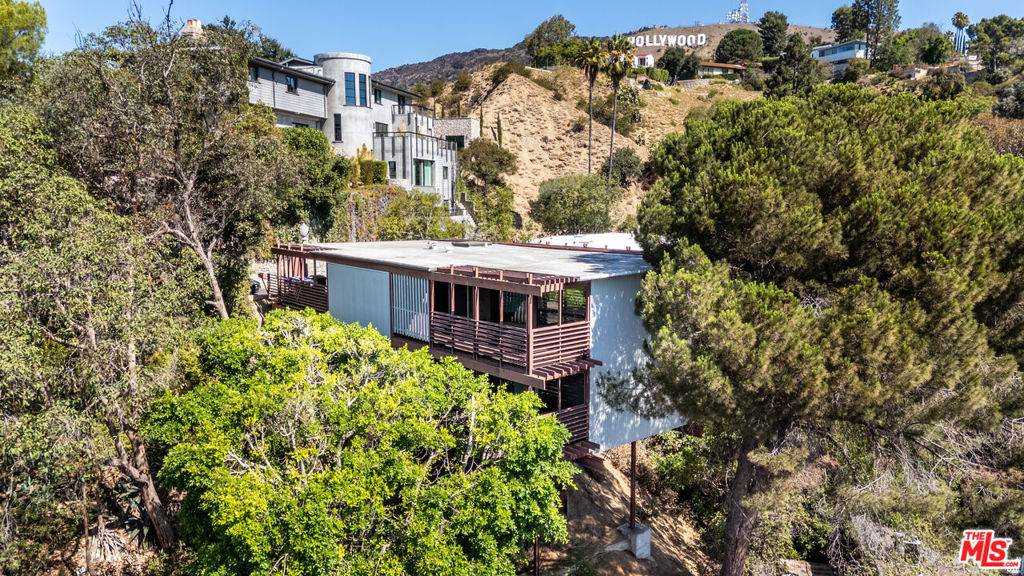 Architecturally significant mid-century modern home designed to capture its hillside setting. This two-bedroom, two-bath residence offers a unique floor plan with both bedrooms, a full bath, and utility room located on the lower level. The upper level features an open layout with quarter bath, kitchen, dining area, and family room, each with direct access to private patios. Large windows and sliding doors provide natural light throughout and showcase views of the surrounding trees and canyon from nearly every room. Quiet and private, this property offers a rare opportunity for those seeking a distinctive mid-century design with a strong connection to its natural surroundings. Ideally located near Griffith Park and Observatory, the Hollywood Reservoir, numerous hiking trails, and an array of charming local eateries, this home combines architectural character with access to some of Los Angeles' most desirable amenities.