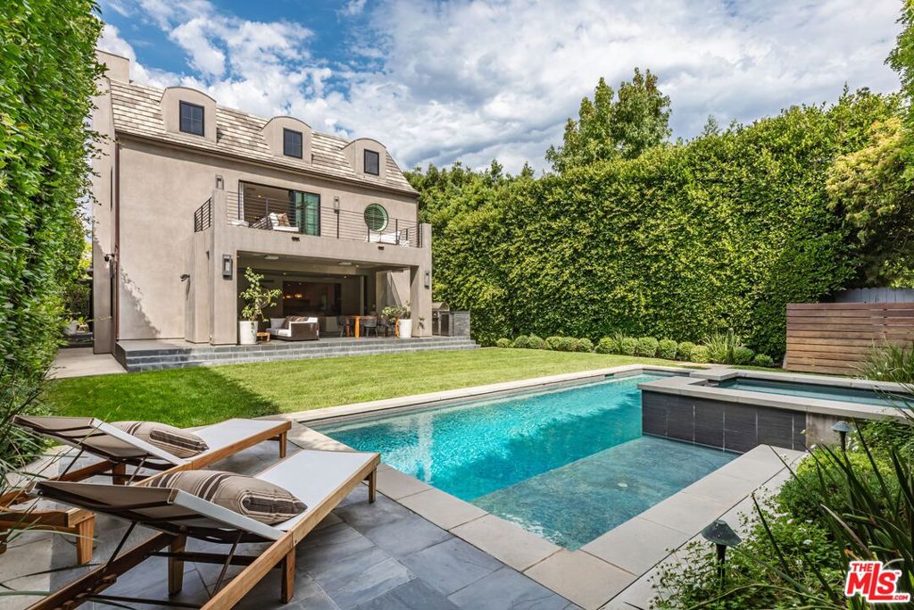 This Brentwood Flats home has been beautifully reimagined, infusing every corner with warmth and sophistication. Set on a 9,007 SF lot on one of the neighborhood's most coveted streets, it seamlessly blends traditional character with a modern, family-friendly 7,474 SF floorplan with 6BD and 8BA. Sunlight pours in throughout, highlighting the exceptional craftsmanship and bespoke finishes. The main level offers an inviting living/family room, formal dining room, flexible guest suite or office, and a stunning kitchen featuring a Lacanche range, oversized island with seating for six, and a cozy breakfast nook. Upstairs, a family room with treetop views anchors four bedrooms - 3 en suites plus an expansive primary suite complete with a balcony, fireplace, bar, and spa-like bath. The lower level is designed for entertaining and wellness, with a bar, wine cellar, gym/massage room, screening room, guest suite, and powder room. Pocketing sliding glass doors on the main level create a seamless indoor-outdoor flow. Outside, lush greenery surrounds a covered patio with a built-in BBQ, dining area, fireplace, swimming pool, and a spa with a cascading waterfall feature. This rare offering captures the best of Brentwood living with timeless elegance and effortless California lifestyle.