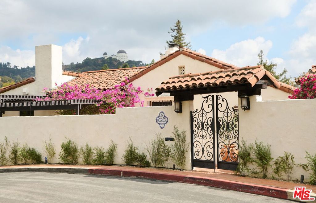 Timeless and enchanting, this 1925 Spanish in the prestigious Los Feliz Oaks is sited on two separate lots and offers a rare combination of privacy, character, and iconic views. Walled and gated from the street, a charming courtyard welcomes you into a home rich with preserved original details. The sunny living room is framed by treetop vistas and unobstructed Downtown LA views, while an updated chef's kitchen blends modern convenience with classic style. Immersed in greenery and nature, enjoy unencumbered views of the Griffith Observatory from multiple vantage points. Downstairs, three bedrooms each feature ensuite bathrooms and outlooks to mature oak trees, creating a serene and secluded retreat. Outside, a large pool, multiple patios, and lush landscaping offer opportunities for entertaining or quiet retreat. Just minutes from the best restaurants and hiking trails in Los Angeles, this is a rare offering in one of the city's most storied neighborhoodsready for its next chapter.