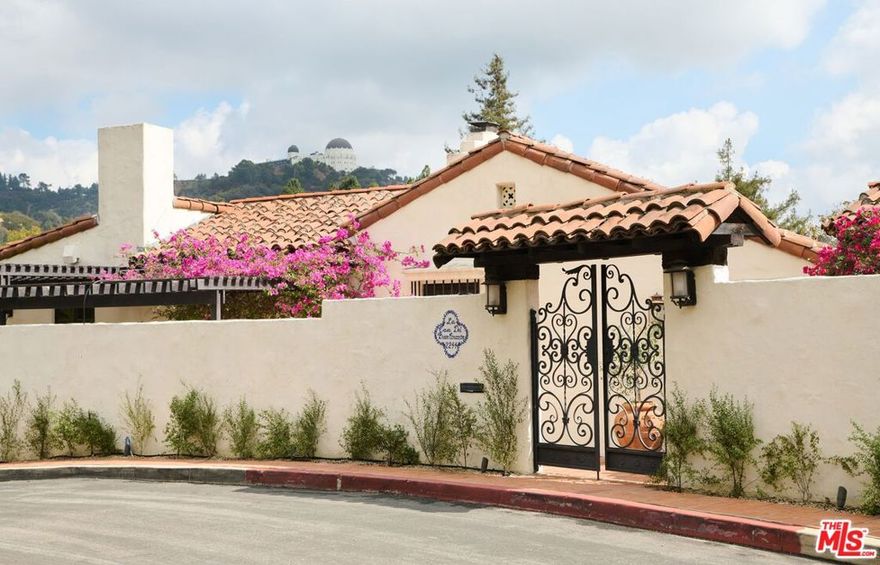 Timeless and enchanting, this 1925 Spanish in the prestigious Los Feliz Oaks is sited on two separate lots and offers a rare combination of privacy, character, and iconic views. Walled and gated from the street, a charming courtyard welcomes you into a home rich with preserved original details. The sunny living room is framed by treetop vistas and unobstructed Downtown LA views, while an updated chef's kitchen blends modern convenience with classic style. Immersed in greenery and nature, enjoy unencumbered views of the Griffith Observatory from multiple vantage points. Downstairs, three bedrooms each feature ensuite bathrooms and outlooks to mature oak trees, creating a serene and secluded retreat. Outside, a large pool, multiple patios, and lush landscaping offer opportunities for entertaining or quiet retreat. Just minutes from the best restaurants and hiking trails in Los Angeles, this is a rare offering in one of the city's most storied neighborhoodsready for its next chapter.