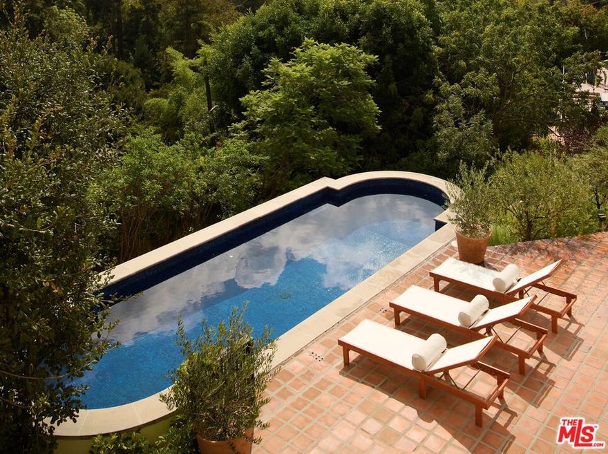 Timeless and enchanting, this 1925 Spanish in the prestigious Los Feliz Oaks is sited on two separate lots and offers a rare combination of privacy, character, and iconic views. Walled and gated from the street, a charming courtyard welcomes you into a home rich with preserved original details. The sunny living room is framed by treetop vistas and unobstructed Downtown LA views, while an updated chef's kitchen blends modern convenience with classic style. Immersed in greenery and nature, enjoy unencumbered views of the Griffith Observatory from multiple vantage points. Downstairs, three bedrooms each feature ensuite bathrooms and outlooks to mature oak trees, creating a serene and secluded retreat. Outside, a large pool, multiple patios, and lush landscaping offer opportunities for entertaining or quiet retreat. Just minutes from the best restaurants and hiking trails in Los Angeles, this is a rare offering in one of the city's most storied neighborhoodsready for its next chapter.