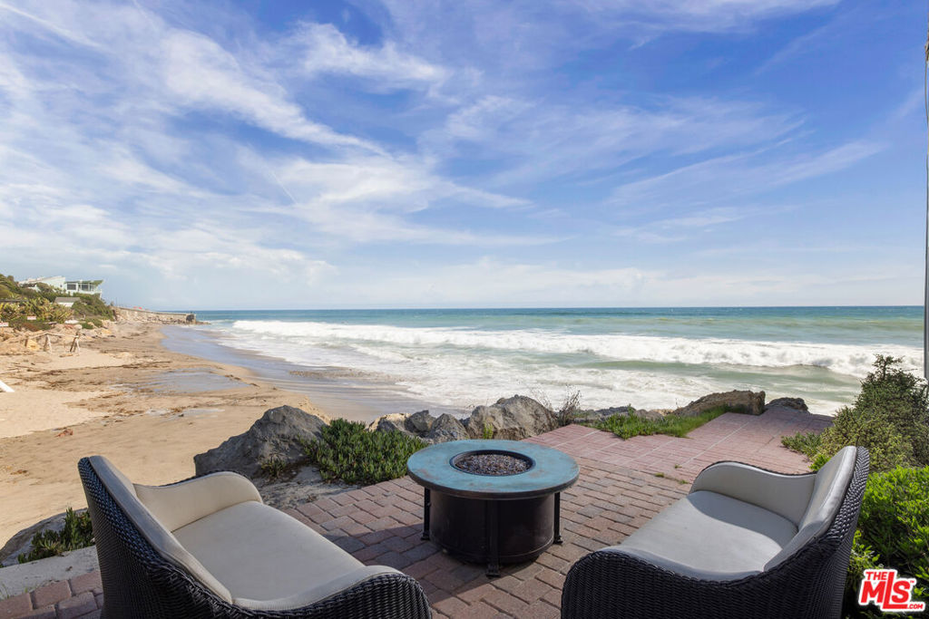 Who wouldn't want to live on the beach? Be the fortunate one to own this fabulous home, perfectly sited offering not only stunning ocean views in front but also unobstructed whitewater coastline views to the side from nearly every room in the house, and from every bedroom. Perched on a small promontory that extends beyond the neighboring houses, this turnkey home is a true dream come true. Imagine waking up to the sound of waves and stepping out through a sliding glass door that leads directly onto the beach via a private pathway. This is the closest thing to having your own private beach in California. Inside, the house is equipped with top-of-the-line Viking stainless steel appliances, ensuring your culinary adventures are nothing short of exceptional. The beachfront deck is perfect for enjoying sunsets, while the remodeled bathrooms and built-out closets add a touch of modern elegance. There are exquisite built-ins in the living room and the primary bedroom, adding both style and functionality. The primary bedroom also features a retractable TV within the cabinetry for your viewing pleasure. With stone floors downstairs and wood floors upstairs, the house exudes a seamless blend of sophistication and comfort. Your private sandy sitting area beside the house offers a serene spot for relaxation, and the wine cellar is ideal for the connoisseur. The main house features 2 bedrooms and 2 1/2 baths, providing ample space for family and friends. The detached guest house, with 1 bedroom and 1 bath, offers an astounding ocean view that will captivate your guests. The open-air courtyard is your private outdoor oasis, perfect for barbecues or cozying up by a fire pit. Parking is a breeze with a 2-car garage and room for 2 additional cars. Nestled behind gates and close to a famous surf spot, this property is truly one of a kind. Just move right in to experience the best of Malibu living.