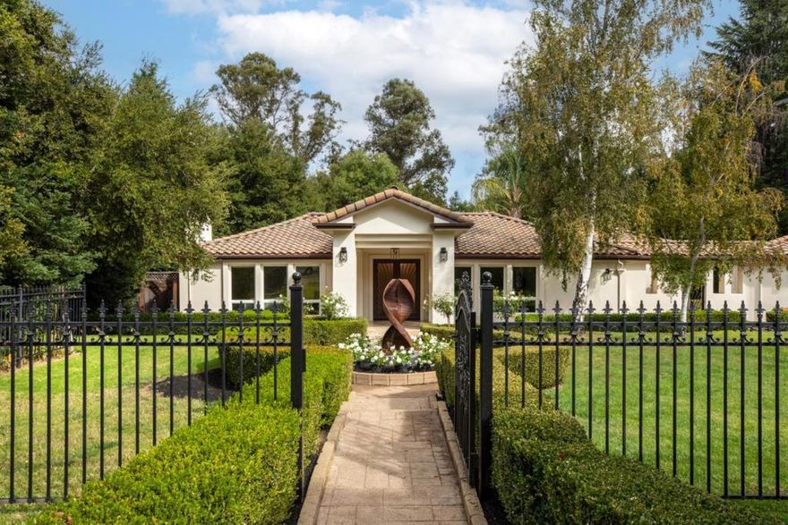 At the entrance to the sought-after Pink Horse Ranch neighborhood, this home spans over one acre with seasonal Adobe Creek at the rear. Originally designed by Wendell Roscoe, the developer of Pink Horse Ranch, the one-level home was renovated and expanded in 2007. Polished marble floors in contrasting hues, vaulted tray ceilings, and wall sconce lighting are signatures of the home today, which opens through impressive artisan crafted front doors. The interior combines privacy and sophistication with elegant formal venues, a spacious gourmet kitchen, family room, plus flexible-use room perfect for an office, playroom, or fitness center. There are 4 bedrooms, 3 full baths, and 2 half-baths with solar-powered electricity. Outdoors, a sparkling solar-heated pool awaits on very private grounds with vast stretches of lawn and expansive terrace. The home's prime location is just minutes to scenic hiking trails, Foothill College, Highway 280, and excellent Los Altos schools.
