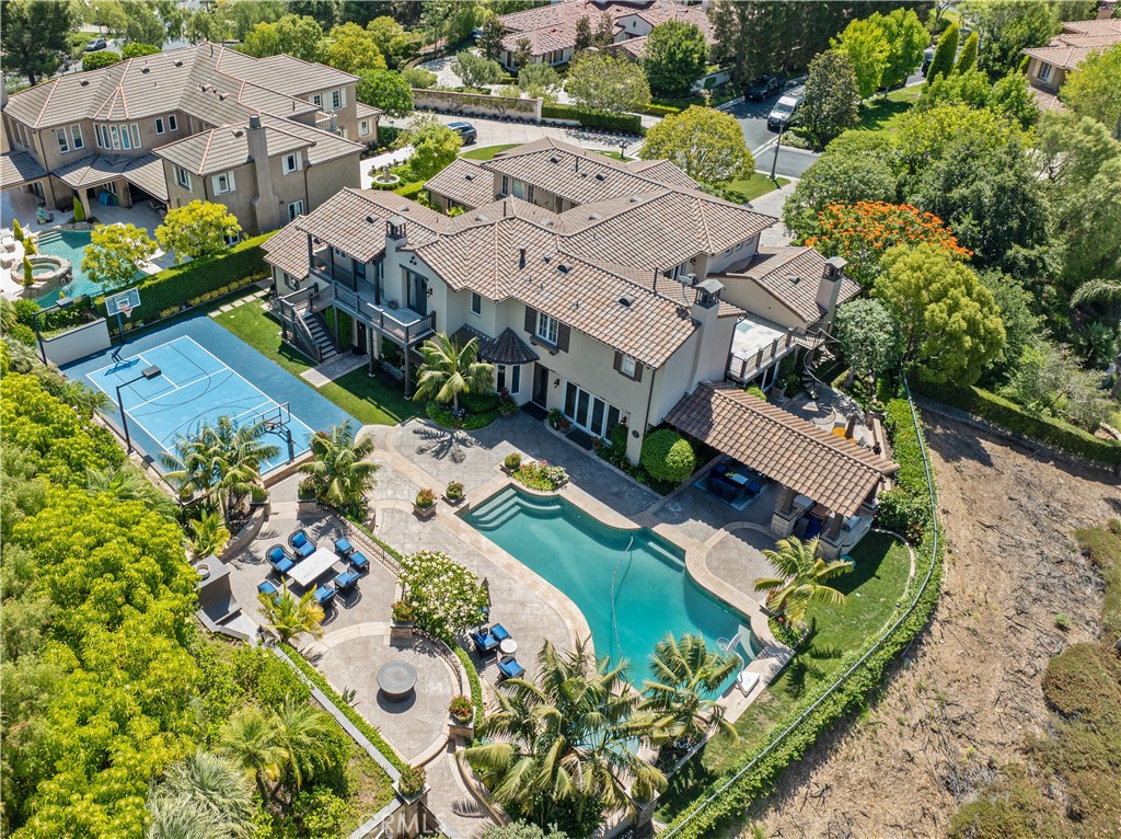 Incredible opportunity to own a show-stopping estate in the prestigious, guard-gated Tustin Ranch Estates! This home sits on a massive 24,829 sq ft corner lot at the end of a quiet cul-de-sac and offers over 5,600 sq ft of beautifully designed living space. Inside, you'll find 5 spacious bedrooms, 6 baths, formal living and dining rooms, a great room, separate family room, executive office, gym, private entrance guest casita, and more. The kitchen has been opened up and refreshed with matte-finish black stone countertops, freshly painted cabinetry, and top-tier appliances including a 6-burner range, double ovens, and built-in refrigerator. Throughout the home you’ll find new lighting, ceiling fans, and freshly painted walls. Additional upgrades include cleaned and sealed stone floors, new wood gates, resurfaced sport court, repainted exterior stucco, and a five-camera Ring security system. The primary suite is a dream, featuring a cozy fireplace, spa-like bath with soaking tub and walk-in shower, a huge walk-in closet, and personal balcony. Step outside to your private resort: pool and spa, multiple patios, outdoor fireplace, built-in BBQ, cabana, and basketball court! Gated 3-car garage, motor court driveway, and lush, manicured landscaping complete this incredible property. Homes like this rarely hit the market, you don’t want to miss it!