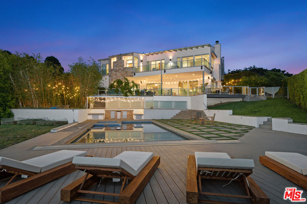 Set behind gates in one of Malibu's most exclusive enclaves and bordered by protected parkland, this architectural estate offers an unparalleled sense of peace, privacy, and year-round sunset views. Resting on two lush acres, this coastal-modern residence was thoughtfully designed to blend luxury, comfort, and effortless indoor-outdoor living.Expansive and filled with natural light, the home features soaring ceilings, floor-to-ceiling windows, skylights, and custom white oak floors throughout. At the heart of the home is a dramatic open staircase that anchors spacious living areas, including two living rooms, a family room, formal dining, and a chef's kitchen with oversized center island and dual breakfast areas all opening to an approximately 2,000 sq ft wraparound tiled deck with breathtaking vistas of the pool, gardens, and horizon. You'll find six bedrooms and seven bathrooms in total five of which are ensuite and four with private balconies and views. The primary suite is a private retreat with fireplace, oversized balcony, dual spa-inspired bathroom, walk-in closets, and unobstructed sunset views. The resort-style grounds are extraordinary: a sparkling pool and spa with spacious lounging areas, a Zen bamboo garden with built-in gas firepit, a rose garden, organic orchard, vegetable and herb beds, grassy lawn, and enclosed pet area all surrounded by mature landscaping and parkland. Additional upgrades include automated blinds, blackout drapery, interior/exterior sound system, hard-wired Ring security cameras, Nest climate control, new recessed lighting, and a three-car garage with dedicated EV chargers. A rare offering that checks every box: privacy, views, modern design, and seamless lifestyle in a prime, gated Malibu location just minutes to PCH.