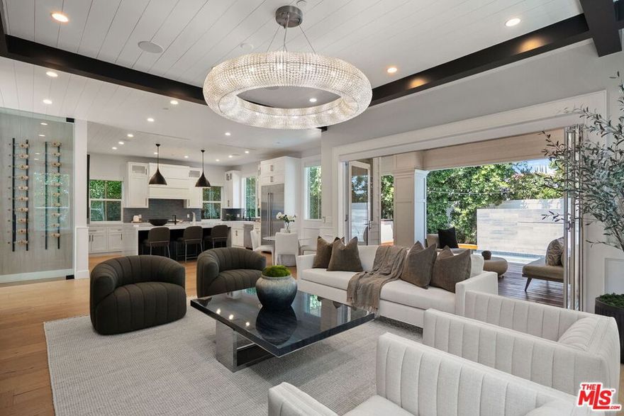 Big news! $150,000 price adjustment! Don't miss out on classic East Coast elegance, seamlessly blended with modern California living. With a newly adjusted price, this property combines timeless appeal with outstanding value. Privately gated and masterfully crafted, this five-bedroom, five-bathroom estate is nestled south of Ventura Boulevard on one of Encino's most desirable streets. Spanning over 3,600 square feet of refined interiors and resort-caliber amenities, this home offers elevated living at every turn. A gated front courtyard welcomes you into a serene garden sanctuary featuring lush landscaping, a vegetable and flower garden, and a peaceful sitting area. Step inside the grand foyer where double-height ceilings soar over 20 feet, accented by intricate moldings and a dramatic statement staircase and hand-blown glass chandelier. Wide-plank European oak floors in rich natural tones contrast beautifully against bespoke black coffered ceilings, setting the stage for timeless sophistication. The formal living room is anchored by a stately fireplace and surrounded by oversized windows, offering warmth and light in equal measure. The elegant dining room features mirrored paneling and designer lighting, creating the ideal backdrop for intimate dinners or festive gatherings. A butler's pantry leads to the showpiece of the home, the family kitchen. Open to the family room and anchored by a massive center island with waterfall quartz countertops, this chef's kitchen is outfitted with premium JennAir appliances, custom cabinetry, and a built-in wine display wall. The space flows seamlessly into the sun-drenched breakfast area and inviting family room with modern fireplace and an indoor-outdoor experience through expansive glass accordion doors. Upstairs, the primary suite is a private retreat with a fireplace, vaulted ceilings, and French doors opening to a sprawling balcony with treetop and canyon views. The spa-inspired bathroom offers a freestanding soaking tub, dual vanities, oversized rain shower, and boutique-style walk-in closet. Additional upstairs bedrooms are all ensuite and beautifully appointed with access to balconies. The backyard is a true oasiscomplete with a sparkling pool and spa with a waterfall feature, custom wood decking, built-in barbecue, covered patio, and multiple areas for lounging and entertaining. Additional features include a spacious main-level guest suite, upstairs laundry room, integrated surround sound, smart home technology, automatic blackout shades, wired security system, and a two-car garage with direct entry. This home offers easy access to Encino's finest amenities including top-rated schools, Equinox, Trader Joe's, Encino Commons, Balboa Park, Los Encinos State Historic Park, El Caballero Country Club and the 101 freeway. Whether you are dining out, shopping, or seeking nature and wellness, everything is just minutes away.