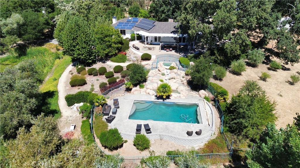 Set within the coveted Chandler Ranch neighborhood in West Atasacadero, this 3.93-acre estate captures the essence of living on the Central Coast. Offering 5 bedrooms and 3.5 baths, the residence was originally crafted in 1983 and has since been tastefully renewed with modern upgrades. The heart of the home is its beautifully remodeled kitchen, featuring marble counters and accent backsplash, custom cabinetry, and seamless flow to an expansive outdoor patio paved in stone, where a fire pit, pergola, and integrated speakers create the perfect atmosphere for gatherings.
The interiors balance sophistication with comfort. A newly finished laundry room combines large slate flooring with abundant storage, while the subterranean wine cellar, lined with cork and built for 280 bottles, adds character and function. Flexible living spaces include a cozy game room with fireplace, a private office with built-in cabinets, and a dedicated fitness room. Upstairs, every bedroom opens to a private balcony or deck, and the primary suite stands apart with dual walk-in closets, spa-inspired bath, heated tile floors, a steam shower, and a deck designed for moonlit views overlooking the private lake.
Outdoor living is elevated by a cascading water feature: the spa gently spills into a shallow kiddie pool before reaching the main pool all surrounded by a secure perimeter fence. Beyond the pool, you’ll enjoy your own private lake stocked with bass and catfish which has been the centerpiece of the property for decades, bordered by mature oaks, fruit and nut trees, and wildlife . With dual solar systems, EV charging, and a fully pavered driveway, this estate delivers both efficiency and timeless appeal. A rare offering in one of Atascadero’s most desirable neighborhoods, 8189 San Dimas Rd presents a lifestyle of beauty, privacy, and distinction.