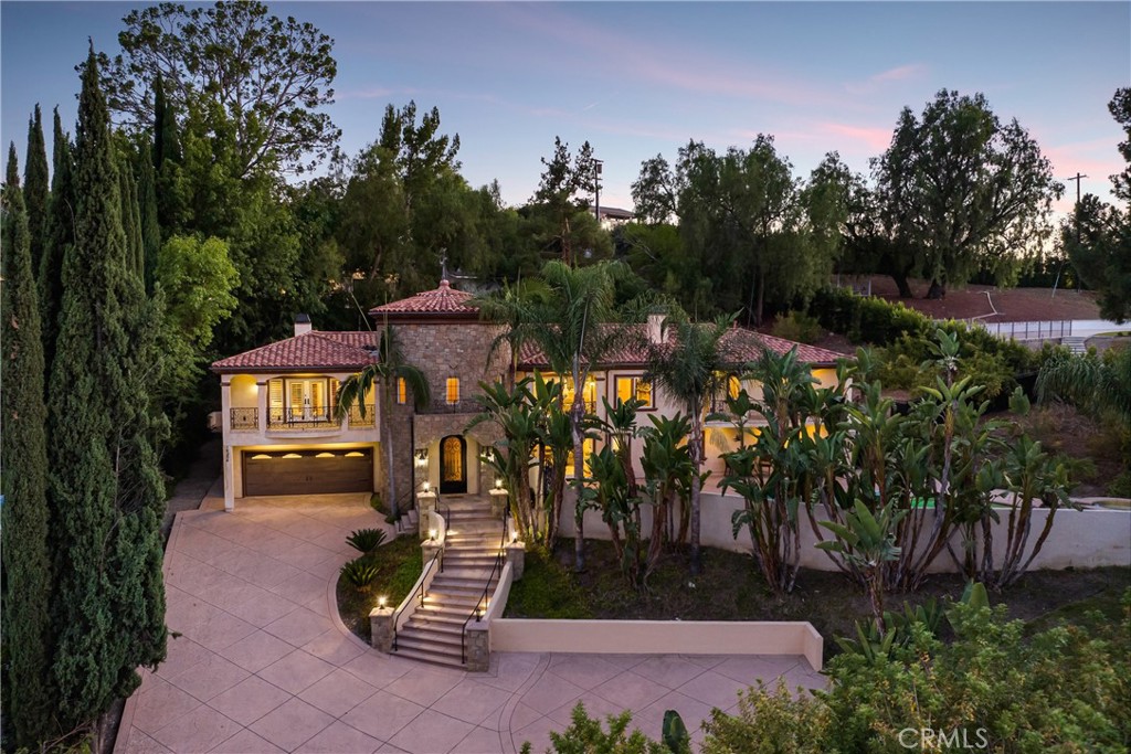 Behind private elegant gates, this breathtaking residence offers timeless elegance, privacy, and panoramic valley views. A grand 25-ft entry tower with Venetian plaster, dramatic banisters, and exquisite flooring sets the tone for the craftsmanship found throughout.
The gourmet chef’s kitchen features granite counters, custom cabinetry, Viking appliances, and a large center island with garden views—perfect for entertaining. Two main-level bedroom suites, a full bar, wine room/humidor, dumbwaiter, and laundry chute add convenience and luxury.
The primary retreat is a true sanctuary with Brazilian cherry wood floors, Carrera marble spa bath, fireplace, wet bar, balcony, and dual walk-in closets. Additional en suite bedrooms provide comfort and privacy for family and guests.
Resort-style outdoor living awaits with a sparkling pool & spa, Viking BBQ, fire pit, and expansive entertainer’s patio. A rare 6-car tandem garage ensures ample parking, while lush landscaping and long private driveway offer seclusion.
Built with no expense spared, this estate blends Old-World charm with modern amenities. Close to golf courses, hiking trails, Ventura Blvd dining, shops, and more. This home defines luxury living in prime Tarzana.