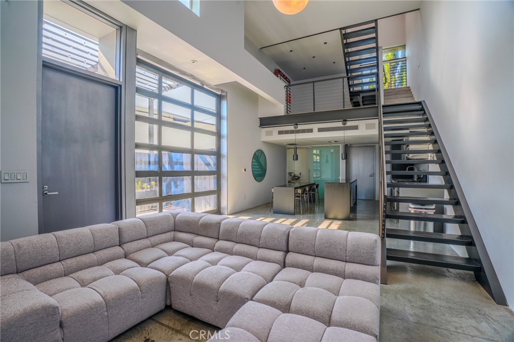 West Hollywood living at its finest! Located in a highly sought after AIA Award-Winning Building, designed by prolific Architects Pugh-Scarpa! This modern architectural gem has been intricately designed to captivate the senses of any contemporary design enthusiast. Soaring 17-foot ceilings create an expansive, light-filled living space with effortless indoor-outdoor flow. The living space has polished concrete floors, large pocket windows, and a sliding metal-and-glass wall which opens to an oversized patio— complete with planter boxes, pergola, and high privacy fencing that is a perfect place for entertaining and relaxing. On the second level is a mezzanine-style office/flex space overlooks the living room, offering a dynamic and inspiring workspace. The top-floor primary suite features floor-to-ceiling windows with sweeping views of the Hollywood Hills. A flexible second room at the top level could potentially be used as a guest room, den, or studio. The spa-like primary bathroom includes a glass-tiled walk-in shower and tranquil ambiance. Other great features of the home include a Sub-Zero refrigerator, Dual Zone AC, and Ample storage throughout. Also includes gated subterranean parking and an HOA common area animal space/run at the back of the lot. All just moments from iconic Hollywood and L.A. landmarks—perfect for urban dwellers and design lovers alike.