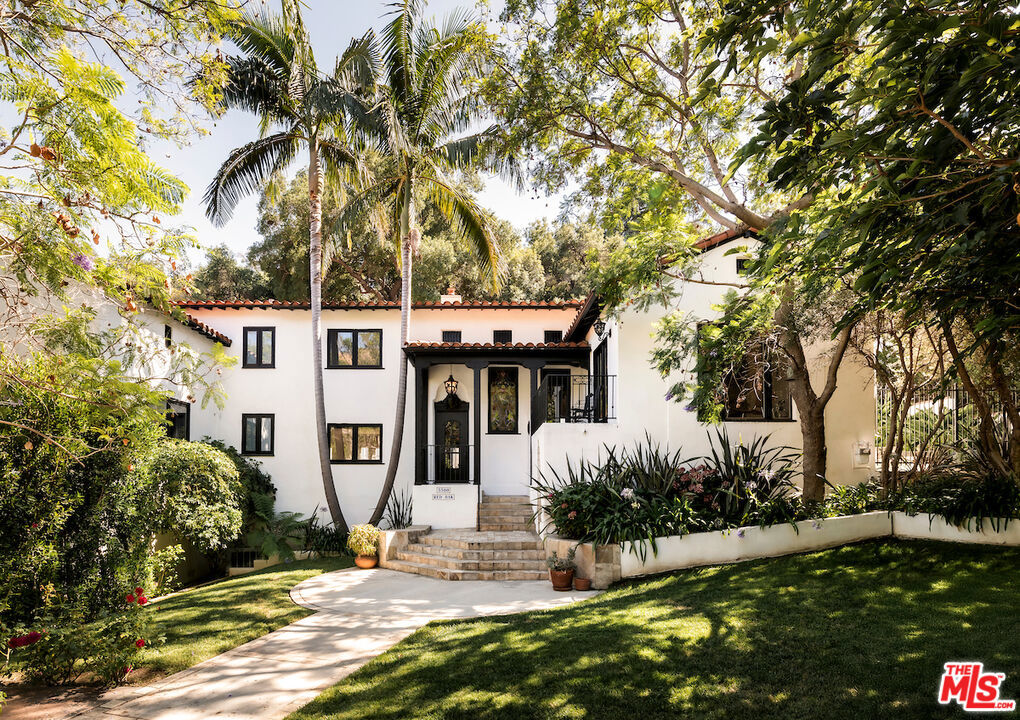 Nestled in Los Feliz' sought-after "Oak Streets," this reimagined 4-bed, 5-bath Contemporary Spanish estate seamlessly blends historic charm with modern luxury. From the gated drive and lush landscaping to arched windows and exposed beams, every detail feels curated and inviting. Perfectly positioned between Beachwood Canyon and Los Feliz, the home offers rare dual access ideal for those who love the Eastside's character yet want the convenience of an easy connection to Hollywood and beyond. The sunlit living and dining rooms flow into a soaring double-height family room, while the chef's kitchen overlooks a stunning oversized mosaic-tiled pool. Designed for entertaining, the backyard features a pergola lounge with fireplace, outdoor kitchen, and spa all framed by views of Griffith Observatory in total privacy. Upstairs, the primary suite offers dual walk-in closets, a spa-like bath, and a private fireplace. Three additional bedrooms provide easy access to updated bathrooms, custom built-ins, and flexible spaces for family, guests, or a home office. Offered fully furnished, this residence invites you to embrace elevated living where classic design meets modern convenience, just minutes from Griffith Park trails, the Trails Cafe, and the best of Los Feliz.