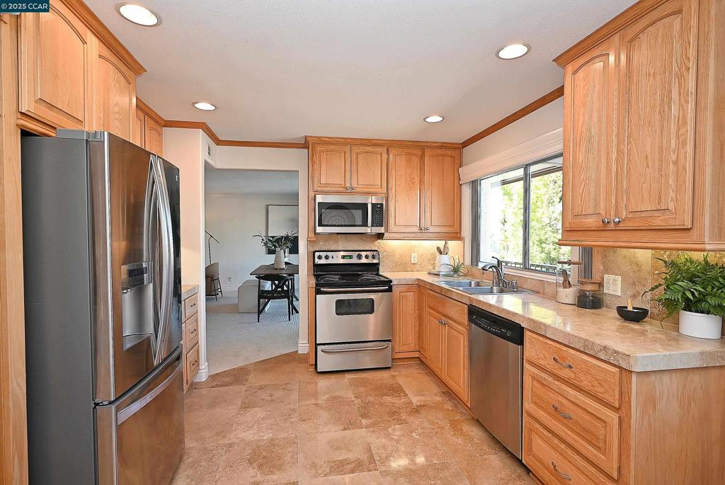 Tucked against a peaceful wooded slope at the end of a quiet entry shared by only two buildings, this beautifully updated condo offers rare privacy with no shared walls. Flooded with natural light, the home features extensive travertine finishes on floors, counters, and backsplashes, complemented by new carpet in the bedrooms, living and dining areas. The eat-in kitchen sports a walk-in pantry. Enjoy year-round comfort with decks off the living room and primary bedroom, a cozy fireplace, and dual pane windows throughout. Elegant crown molding, substantial baseboards, and custom window sconces enhance the refined atmosphere. Nearby swimming pool for the exclusive use of the neighborhood. Carport #73 with adjacent golf cart parking is conveniently located just outside the front door. Immaculately maintained and move-in ready, this home invites you to settle in and enjoy all that Rossmoor has to offer.