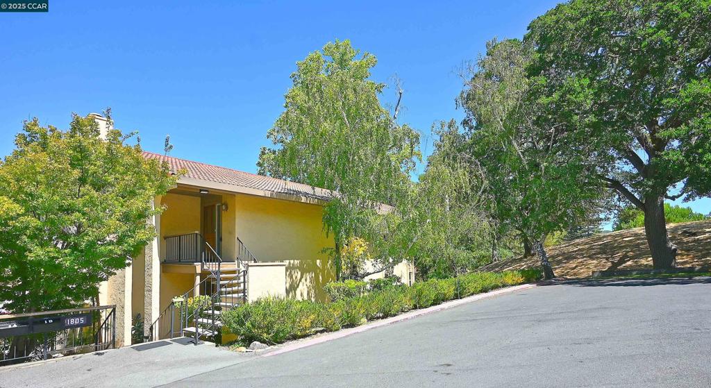 Tucked against a peaceful wooded slope at the end of a quiet entry shared by only two buildings, this beautifully updated condo offers rare privacy with no shared walls. Flooded with natural light, the home features extensive travertine finishes on floors, counters, and backsplashes, complemented by new carpet in the bedrooms, living and dining areas. The eat-in kitchen sports a walk-in pantry. Enjoy year-round comfort with decks off the living room and primary bedroom, a cozy fireplace, and dual pane windows throughout. Elegant crown molding, substantial baseboards, and custom window sconces enhance the refined atmosphere. Carport #73 with adjacent golf cart parking is conveniently located just outside the front door. Immaculately maintained and move-in ready, this home invites you to settle in and enjoy all that Rossmoor has to offer.