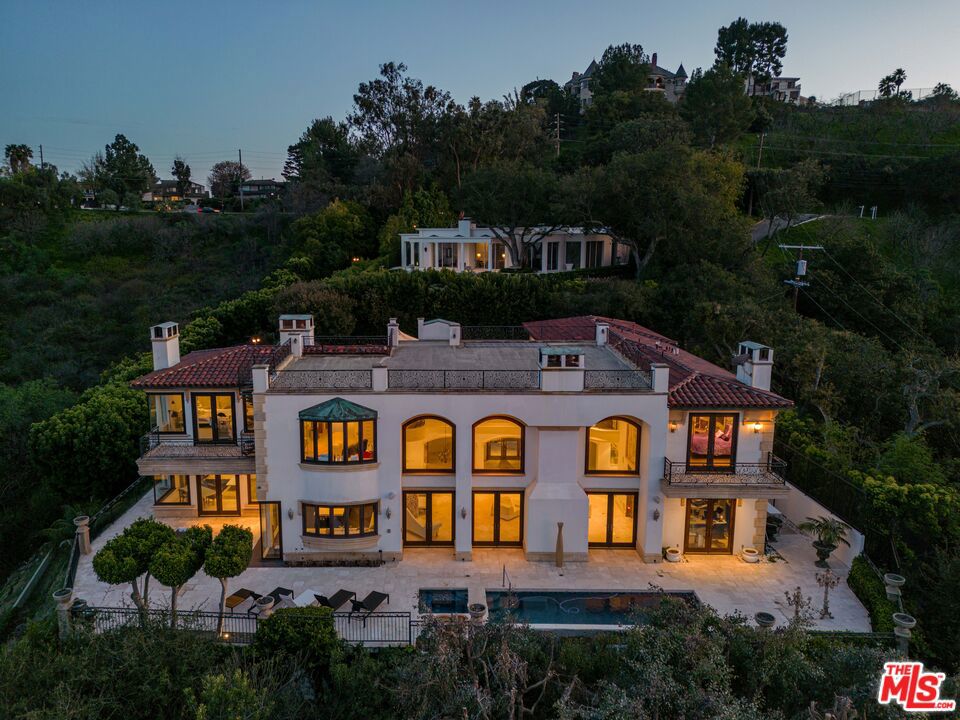Gated long wide driveway leads one to this uniquely private view property on huge flat pad on prestigious star studded Mulholland Drive. This European villa is situated at the end of a long scenic driveway encompassing spectacular 180 degree views across the valley. The driveway approaches a lush large motor court with ample parking for 10 + cars along with a 3 car garage. Upon entering the grand foyer, you are greeted with soaring ceilings and breathtaking columns and archways that open onto a massive great room perfect for large scale entertainment. This perfectly faces the large flat back yard and grounds and stunning views framed by romantic glass doors and windows framing a stunning 8' fireplace. This main level also includes a guest room, a gym, beautifully finished powder rooms complete with Terrazzo floors, a dining room with terrace and a large office which also faces the manicured grounds. The large scale newly remodeled kitchen is an entertainer's dream wrapped up in tasteful modern design. This includes clean custom cabinetry, state of the art Miele appliances, quartz countertops, natural lighting and a breakfast bar opens to a a spacious family room continuing the indoor/outdoor flow opening onto to a large outdoor entertaining area which includes a luxurious pool and spa. The grand staircase is detailed with a European style mural leading up to the newly redone second floor walkway. The expansive Primary suite is situated at the top of the stairs behind large ornate doors. Ample natural night, a fireplace, large walk in closet, and a modern bathroom compete the suite. This home is a perfectly serene villa that is a total retreat from the bustling LA lifestyle.