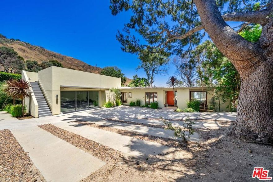 Perched above the Pacific in Malibu's coveted Big Rock community, this extraordinary Mid-Century Modern home offers a rare fusion of sophistication and serenity. Owned by the same family for many years and painstakingly improved with meticulous care year after year, the residence embodies both timeless craftsmanship and modern refinement. Thoughtfully expanded with intentional square footage, it now includes a versatile flex space and dedicated office, complementing the home's original architectural integrity. Designed with the essence of a Zen retreat, this ultra-private 4-bedroom, 3-bath gated masterpiece once featured in Sunset Magazine effortlessly balances organic textures with timeless contemporary elegance. Every detail has been carefully curated, from warm wood finishes and artisanal tile work to striking designer accents and top-tier materials that elevate the home's aesthetic. Walls of glass invite natural light to cascade through open-concept living spaces, creating a seamless indoor-outdoor flow that enhances both intimacy and entertainment. Step outside to a resort-style oasis featuring a saltwater pool and spa, lush grassy yard, an incredible ocean view, fire pit lounge, and an alfresco kitchen with a fully equipped BBQ all framed by ocean breezes and tranquil greenery. Ascend to the private rooftop deck for panoramic sunrises and sunsets that stretch across the Pacific Ocean and Queen's Necklace. Sustainable living is also woven into the home's core, with full solar power, two Tesla Powerwalls, an EV charging station, and dual gated access to a circular driveway. Ideally located just minutes from Santa Monica, central Malibu, and some of California's most iconic beaches and hiking trails, this is coastal living at its most refined.