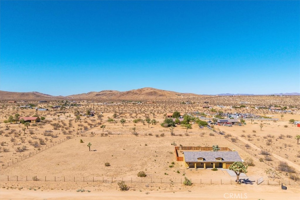 Welcome to your beautiful ranch-style home in peaceful North Joshua Tree! Sitting on 2.5 acres with dormer windows, arches, and sweeping panoramic desert and mountain views, this 3 bedroom, 2 bathroom home offers both charm and modern comfort with no visual power lines to impede the views
.Step inside to find high ceilings and a cozy fireplace in the main living area, which flows seamlessly into the dining room and kitchen. The kitchen is a highlight with granite tile countertops, freshly painted cabinets, stainless steel appliances, breakfast bar, and a picture-perfect window view above the sink. Sliding glass doors off the dining area lead to a large covered patio—perfect for entertaining or enjoying tranquil desert nights.
The spacious bedrooms are bright and airy, each with concrete floors and ceiling fans. The primary suite includes a large walk-in closet, slider access to the back patio, and a private bath with a walk-in shower and matching granite finishes. The guest bath features a tub/shower combo and granite vanity.
Additional features include:Fully fenced property with a wooden privacy-fenced backyard area. Underground utilities (no obstructed views!)
2-car finished garage with high ceilings and laundry hookups. Concrete driveway and charming covered front patio
Room for a pool, workshop, or ADU etc. All parcels in this sought-after area are on acreage, ensuring space and privacy. Just 10 minutes to Joshua Tree Village and less than 20 minutes to the National Park, the location balances serenity with convenience.Inclusions: Washer, Dryer, Refrigerator
Imagine starry desert nights from your property with nearly no light pollution—peace and tranquility await. Don’t miss out on this opportunity—schedule your private showing today!Please include a recent pre-approval letter and proof of funds with your offer.Buyer to verify all MLS information, including but not limited to: permits and uses, bed/bath counts, square footage, school information and enrollment availability. Buyer is advised to independently investigate all aspects of the property, and to verify the accuracy of all information provided through personal inspections and with appropriate professionals to the buyer’s satisfaction.Buyer is solely responsible for verifying water, power, zoning, and county building requirements.Buyers are responsible for confirming the accuracy of all information and are encouraged to conduct their own due diligence or retain qualified professionals.