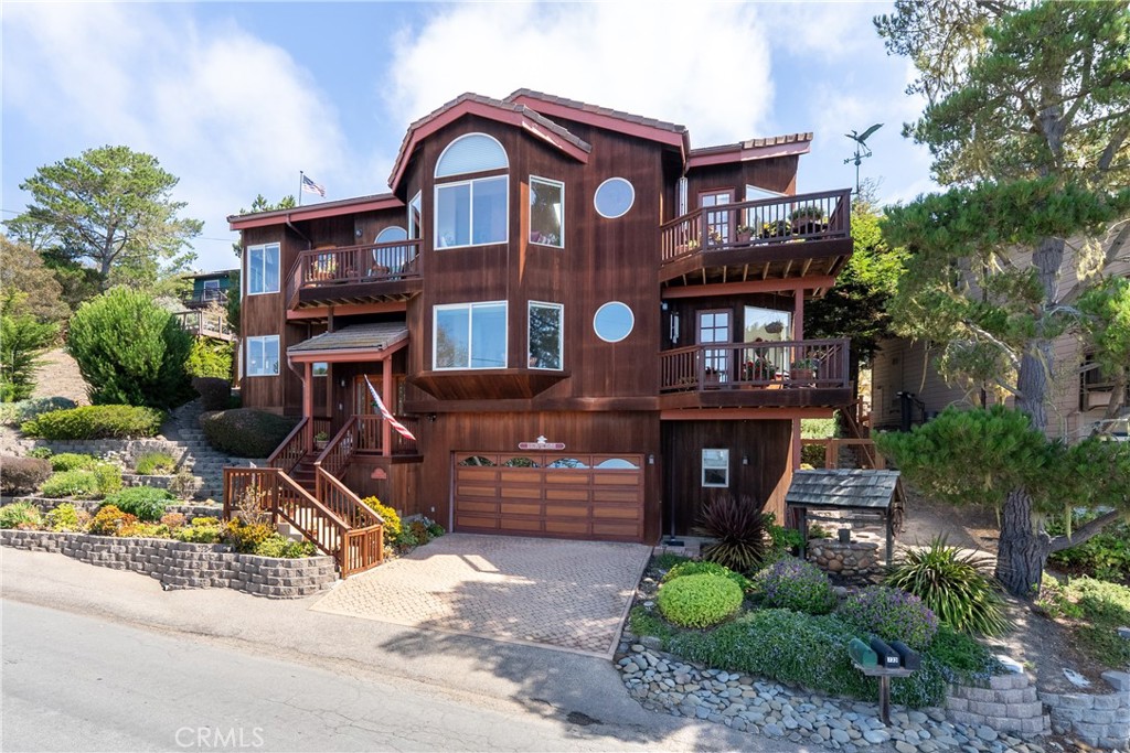 Custom built redwood home designed to capture sweeping ocean views from nearly every room. The open floor plan blends kitchen, dining, and living spaces with walls of westerly windows framing the Pacific, while easterly windows and decks look out over peaceful private gardens. The kitchen is a true centerpiece with custom Corian countertops, handcrafted tile backsplash, a garden window, 36-inch five burner cooktop, custom wood floors, and a shiplap ceiling, all opening seamlessly to the living areas. The living room invites gatherings with its woodburning fireplace, brick hearth, built-in bookcases, and massive window seat. A dumbwaiter provides effortless convenience with an access door on each level, perfect for moving groceries and household items with ease. The primary suite is a private retreat with a gas fireplace, two walk-in closets, spa-like bathroom with jetted tub, separate shower, dual sinks, and a private deck overlooking the Pacific. A second oversized window seat adds warmth and character to the suite. Situated on three lots, the property enjoys drought-tolerant landscaping sustained by an artesian-fed water capture and storage system. Every level features a deck to take in the views, while the concrete tile roof, cobblestone-style driveway, and two-car garage enhance its quality and appeal. Built by sought-after Brian Wilson. Located in one of the most sought-after neighborhoods near both the ocean and Fiscalini Ranch, this one-of-a-kind home pairs custom craftsmanship with coastal living at its finest.
