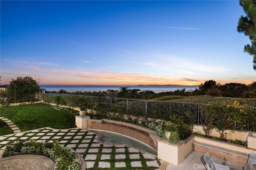This spectacular residence with soothing views of the Pacific, is situated in Pelican Crest, a community that offers homes of substance on a grand scale. Lavish details begin in the courtyard, where a pristine garden and stone edifice showcase the unsurpassed quality of this 11,438 +/- s.f. home with 6 beds & 8 baths on over half an acre. Designed to welcome guests, the entry hall features an exquisite chandelier and ceiling inset with pale blue glass, as well as a bar area for formal entertaining. The gourmet kitchen, along with a large butler’s pantry that adjoins the dining room, are well-suited for serving large gatherings, with Viking appliances geared towards catering. Several sprawling living spaces on the first floor offer finely detailed moldings and access to open terraces with views that skim over lush greenery to encompass the ocean views. A guest suite and wood paneled office are found on the first floor, with garden views through arched windows. Dual staircases ascend to the upper floor, where a calming master suite features a fireplace, private terrace with views of Catalina, and an extravagant ensuite bath with custom vanities and a soaking tub peeking out at treetops. A family room is lined with French doors that open to ocean breezes, and 3 additional bedrooms offer adjoining baths. A walk-out subterranean level offers a spa-like area with an indoor pool, massage area, steam room, sauna & kitchenette, as well as a staff bedroom and bath.
