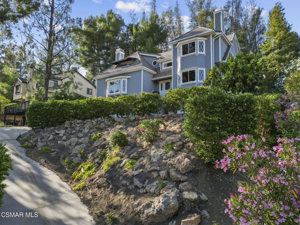 Nestled in a private, serene setting where mountain breezes meet timeless craftsmanship, this nearly 4,000 sq ft custom-built home offers an extraordinary blend of warmth, tradition, and refined elegance. Featuring rich real wood flooring throughout and handcrafted custom wood cabinetry, the home is filled with soul and story, including hand-painted murals inspired by a family farm in Norway that grace the walls with artistry and heart. With 4 bedrooms and 3.5 bathrooms, the spacious layout is designed for both luxurious comfort and everyday functionality. The primary suite is a true retreat, boasting soaring ceilings, stunning mountain views, four closets, including a center island wardrobe station and a spa-inspired bathroom with marble countertops, soaking tub, and a steam shower. The lowest level offers a private suite with separate entrance, bedroom, bathroom, living space, and laundry, ideal for guests, multigenerational living, or a private office. Large secondary bedrooms include one with a private balcony and another with access to a shared, well-appointed bath. Three unique fireplaces anchor the primary suite, family room, and formal living room, while custom built-ins and stainless-steel appliances complement the gourmet kitchen and formal dining space, which also features a wine refrigerator and a substantial wine locker. Nearly every window frames panoramic mountain views, and the property invites outdoor exploration with meandering garden paths, custom stone hardscape, fruit trees, sitting areas, a koi pond, and even a small private forest. Direct access to the back entrance of Malibu Creek State Park makes hiking and adventure effortless. Located in an award-winning school district, just minutes from the freeway and beaches, this home feels a world away yet it's incredibly close to everything. A rare opportunity to live in a place that feels both grounded in nature and elevated in design.