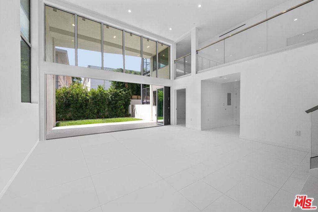 In addition to 1,670 square feet of interior living space, this residence offers over 375 square feet of private outdoor space which consists of a patio with a private yard. Welcome to THE TITANIUM, Unit 2 - Iridium, a rare two-story architectural condominium showcasing soaring 20+ foot ceilings, abundant natural light, and seamless indoor-outdoor flow. This beautifully designed unit includes a versatile top-floor den overlooking the dramatic living room and can serve as a home office, fitness area, or creative retreat/additional bedroom, while the main level opens directly to a patio with a private yard. The home features two matching primary suites, direct elevator access, and two side by side parking spaces in a secure garage. Just steps from iconic Melrose Place, this one of a kind residence combines privacy, style, and convenience in one of West Hollywood's most coveted locations.