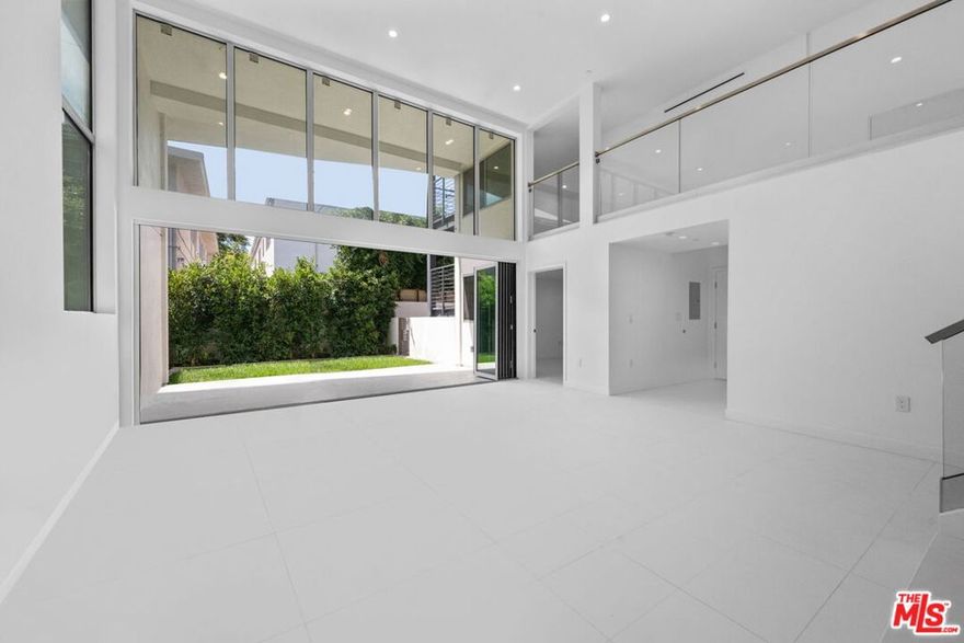 In addition to 1,670 square feet of interior living space, this residence offers over 375 square feet of private outdoor space which consists of a patio with a private yard. Welcome to THE TITANIUM, Unit 2 - Iridium, a rare two-story architectural condominium showcasing soaring 20+ foot ceilings, abundant natural light, and seamless indoor-outdoor flow. This beautifully designed unit includes a versatile top-floor den overlooking the dramatic living room and can serve as a home office, fitness area, or creative retreat/additional bedroom, while the main level opens directly to a patio with a private yard. The home features two matching primary suites, direct elevator access, and two side by side parking spaces in a secure garage. Just steps from iconic Melrose Place, this one of a kind residence combines privacy, style, and convenience in one of West Hollywood's most coveted locations.