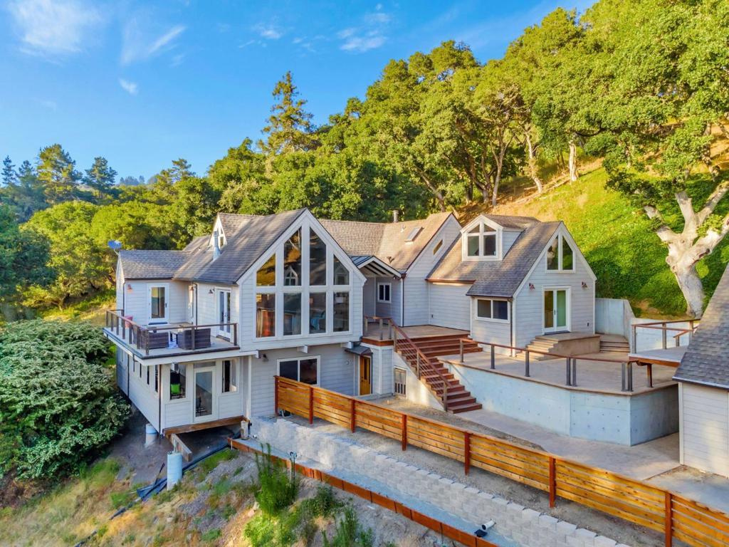 Experience unparalleled luxury & breathtaking panoramic views of Monterey Bay from this exquisite 4 bedroom, 4 bathroom custom estate, boasting 3,279 sqft of sophisticated living space. Nestled on a vast 4.16 acre lot, this property seamlessly combines privacy, comfort & functionality. On the main floor enjoy 2 bedrooms, including primary retreat w/ private bath, guest bath, living room w/ vaulted ceilings, separate dining room overlooking large outdoor balcony w/ views & gourmet kitchen w/ stainless steel appliances & breakfast bar! Private deck off the living room is amazing for viewing those marvelous sunsets! Top story has a cozy office area, living room, full bath, reading/library nook & plenty of storage space. Bottom level has 2 large rooms, private deck, laundry hookup, radiant floor heating & an abundance of storage space. The 4 car detached garage has a loft above & is surrounded by massive deck w/ beautiful views. Below away from the home is a detached 3 car garage & 1200 sqft shop, plus a small storage shed w/ access to a five freight container bunker underneath. Home has over 3,000 feet of decking with two gas hookups for outside entertaining. Copper gutters throughout, fire resistance siding and numerous windows to view the abundant wildlife & spectacular views!