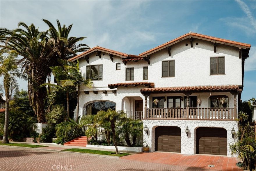 Nestled on a private, gated street in Bluff Park, you will find Vista Del Mar, Harry Broner’s 1930 masterpiece. Vista Del Mar exudes sophistication and understated elegance with fine details such as a grand cathedral ceiling boasting hand-carved wood beams with hand painted embellishments and San Pedro anchor chains, Talavera tiles, wrought iron railings and exterior window details, hand crafted raised panel doors, tray ceilings, textured interior stucco, Moorish arches, and the list continues. A grand entry with circular staircase, wrought iron railings, Spanish red clay tile steps and risers with painted tiles greets you upon arrival. Off to the left is the magnificent living room with a large, arched picture window, stately fireplace, and incredible cathedral style wood beam and iron ceiling. Slightly past the living room is the study with individual wooden beams decorated with hand-painted details. To the right of the foyer is the formal dining room with a crystal chandelier and custom sconces, tray ceiling, double french doors leading to the front balcony, that all lend themselves to the perfect dinner party. Off the dining room is a breakfast nook that is filled with light from multiple windows and a crystal chandelier. The updated kitchen blends original charm with modern Viking appliances.  Beyond the kitchen and through the butler’s pantry is the first of two main level bedrooms with french doors leading to the secluded backyard. Down the main hall you will find the elevator room which services all levels. The second main level bedroom is found at the end of the hall.  The main floor bathroom features basalt mosaic flooring and pale yellow and gloss black wall tile. Follow the grand staircase to the spacious landing on the second level. Two spacious primary suites can be found on this level with one celebrating ocean views, each with direct access to the two period bathrooms featuring separate shower and bath stalls, built-in vanity, decorated in original Catalina tiles and black accents. This level also contains two more bedrooms with balcony access. A lounge with hand-scraped wood beam ceiling, and ocean views through a wall of windows is located adjacent to the bedrooms. A combination of original hardwood flooring and tile are found throughout the estate’s living spaces. On the ground level is a three car garage, laundry room, wine cellar, and elevator landing. This elegant villa is one lot from the beach.