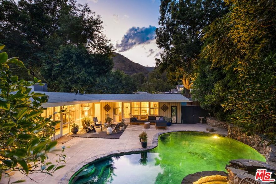 Set in one of Brentwood's most tranquil canyons, this home feels both architecturally significant and deeply serene - a true retreat just moments from the city. Tucked into peaceful Upper Mandeville Canyon, this is a mid-century modern gem set in a very private and protected property. The 3 bedroom, 2 bath home reflects the timeless essence of architectural Cali living with clean lines, natural light, and an easy connection between indoors and out. Designed as a Mid-Century modern by renowned LA architect Allen Siple, the open layout unites the living, dining, and kitchen areas, where walls of glass fill the space with sunlight and frame views of private, lush greenery. The kitchen was recently reimagined with warm oak cabinetry, Zellige tile, brass fixtures, and sleek quartz counters that blend modern design with mid-century character. Open shelving displays curated ceramics, and a large window looks out over the courtyard. The primary suite opens to a private backyard sanctuary with a pool, fountain, and plenty of lounge space for relaxing or entertaining. A bonus and detached 800-square-foot garage and creative studio offer endless possibilities for work or play.
