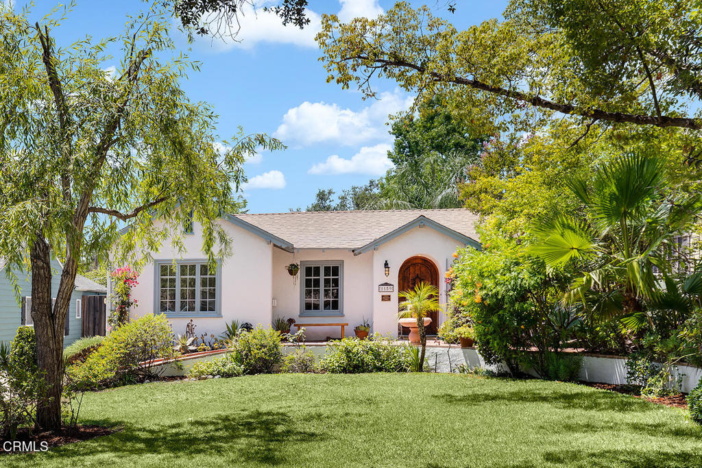Idyllic cottage in Bungalow Heaven offers poolside Provencal lifestyle in Pasadena. This magical 1921-built home offers high-end designer updates as well as down to earth, eclectic charm. Sited just above street level behind a gently curving front wall, this stucco cottage is rich with character details inside and out. A gabled roofline with carved bargeboard and rafter tails complements the recessed arched front door, complete with a speakeasy grille. Inside, luminous hardwood floors welcome visitors into the living room, with handsome original built-in benches framing the decorative original Bachelder tiled fireplace. Enjoy garden views and unique built-in entryway cabinets flanking the front door. A formal dining room with beadboard paneling, built-in corner cabinets and picture rail molding is quintessential arts & crafts style with a twist: a basket pendant light lends a playful contemporary element - a motif repeated throughout. The adjacent gallery space offers possibilities, perhaps a reading room or office? Artful touches continue in the kitchen, where marble countertops, gorgeous deVOL brass fixtures and apron sink elevate the cozy breakfast nook with special hardware and original built-in storage. Open white oak shelving, a deVOL pendant light and upscale Bosch and Fisher & Paykel appliances update this early 20th century kitchen to a modern chef's standards. Slow down with a cuppa, gazing out at the sparkling pool and hummingbirds making the rounds. Three sunny bedrooms and two lovely baths give high-end boutique hotel vibes, with french doors leading to the patio and pool, custom tilework and wallpaper in organic tones, a clawfoot tub and top of the line Waterworks fixtures. The backyard is just as special as the interiors with a happy aqua blue pool, al fresco dining spots, and Wisteria-shaded patio and outdoor fireplace -- this variety of charm can't be manufactured or recreated -- it's the sort thats been honed over a century by a series of stewards who preserved character and enhanced the space with their own artistry. To that end, the two car garage offers space as a studio or potential ADU, with a sunny patio area ready for use as a workshop, grilling station or raised bed gardening. This property, located in one of Pasadena's favorite historic districts, enjoys proximity to all the things. As if it could get any better, the home has been awarded Mills Act status, likely resulting in reduced property taxes for its new owner.