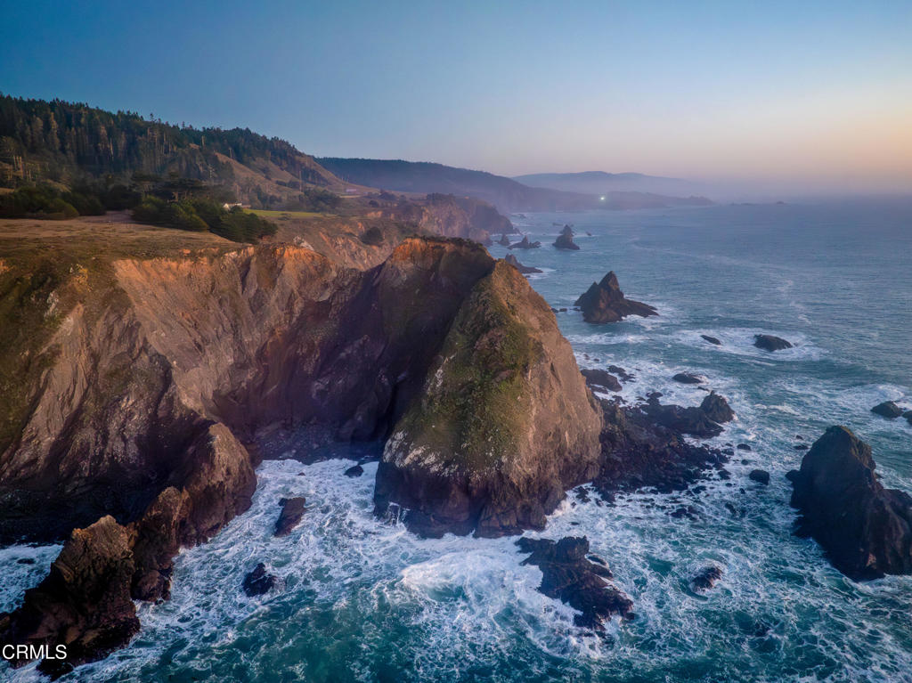 Before maps and boundaries, the relentless Pacific met this ancient stone headland in a timeless dance. Chiseled by wind and wave, the legendary cliffs of Saddle Point have long served as a mariner's compass--its iconic silhouette etched into the memory of all who pass. Here, where the continent yields to the vast Pacific, sits what may be the most significant oceanfront offering in Mendocino County's history. Welcome to Saddle Point Estate--a 56-acre oceanfront sanctuary so remarkable it has graced the pages of National Geographic, Smithsonian Magazine, and even the silver screen. Perched atop nearly a mile of private coastline, this rare compound features three fully permitted residences, grandfathered into county history and embraced by nature's wild poetry. The main house, a stately 3-bedroom, 2-bath home (approx. 1,650 sq ft), anchors the estate with timeless elegance. Nearby, the Ocean View Cottage (2 bed, 1 bath, approx. 825 sq ft) offers comfort with sweeping ocean vistas. The Gardener's Cottage (1 bed, 1 bath, approx. 650 sq ft) rises two stories, capturing panoramic views from a private balcony. A converted redwood barn adds flexible space for art, events, or a workshop. Wander manicured lawns that spill toward the cliffs, where thoughtfully placed viewing decks offer front-row seats to the Pacific's ever-changing canvas. Spot migrating whales, uncover hidden coves, or lose time watching the light play across fifteen miles of coastline, from your perch to the historic Point Arena Lighthouse. Nearly two miles of flat, private trails lead through coastal meadows to secluded beaches and coves, while a modern underground shelter offers a unique layer of privacy and preparedness. Whether envisioned as a legacy family compound, an exclusive retreat, or a coastal hospitality venture, this property adapts with grace and grandeur. Fly into nearby Little River Airport, dine at the acclaimed two Michelin-starred Harbor House Inn, and retreat to a place where the horizon holds no bounds. Three APNs. Endless Possibility. Unmatched Provenance. Saddle Point Estate is more than land--it's a legacy, a compass, a coastal masterpiece.