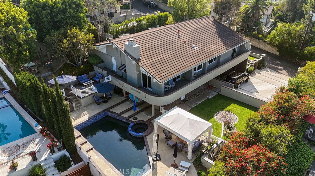 Nestled in prestigious North Tustin, this elegant 4-bedroom, 3.5-bathroom residence offers an impressive 3,400 square feet of well-appointed living space. Uniquely positioned on a tucked away lot off the main streets, this home provides exceptional privacy while showcasing breathtaking views of the surrounding hills. The property features two separate entry points with distinct driveways, providing ample parking space for residents and guests alike - a rare convenience that eliminates parking concerns during gatherings. The versatile floor plan features two separate living rooms - an elegant formal living room perfect for sophisticated gatherings and a comfortable family room ideal for casual everyday relaxation. A dedicated dining room completes the entertainment spaces, offering flexibility for both intimate family meals and larger dinner parties. The gourmet kitchen features a large island that serves as the perfect gathering spot for casual dining and social interaction while preparing meals. Home chefs will appreciate the exceptionally large walk-in pantry, offering abundant storage for groceries, small appliances, Sub-Zero fridge, whole house water filter system and culinary essentials. A standout feature is the versatile large room downstairs, perfectly suited as a dedicated workout space or a private guest retreat that allows visitors to enjoy their stay without interruption to the main living areas. Additional highlights include a refreshing swimming salt water pool and a substantial garage. Located in one of Orange County's most sought-after communities, residents enjoy excellent schools, low crime rates, and a semi-rural atmosphere while maintaining convenient access to shopping, dining, and major transportation routes. The property's secluded setting and elevated vantage point offer an enviable living experience where tranquility and convenience harmoniously coexist. Well-maintained and move-in ready, this home awaits new owners looking to establish themselves in this desirable neighborhood.