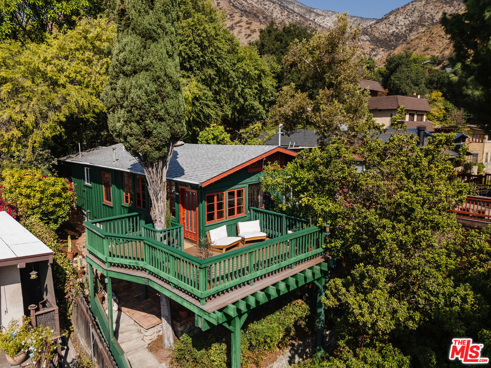 An enchanting blend of canyon charm and thoughtful updates, this 1922 Sierra Madre Canyon cottage offers a serene retreat tucked into the San Gabriel Mountains. A river rocklined driveway leads to a welcoming front porch that wraps around a towering cypress tree, creating a unique treehouse-like perch to enjoy the quiet setting and mountain air. Bathed in natural light, the living and dining room is framed by a wall of French windows that open to leafy canyon views. A cozy office with a built-in desk provides a tranquil space for work or creative pursuits. The kitchen balances vintage character with modern updates, featuring butcher block counters, a gas range, custom coffee cabinet, and ample workspace for cooking and entertaining. Two bedrooms and two baths span two levels, offering flexibility for guests, a home office, or a private retreat. The remodeled primary bath is finished with custom tile and a soaking tub. Outdoors, a flagstone patio extends the living space and creates an inviting backdrop for al fresco dining and gatherings. With its seamless indoor-outdoor flow, thoughtful upgrades, and tranquil canyon setting, this home captures the essence of California living. Tucked away in a peaceful location close to Mary's Market, local hiking trails, downtown Sierra Madre, and nearby Pasadena, it offers both retreat and convenience.