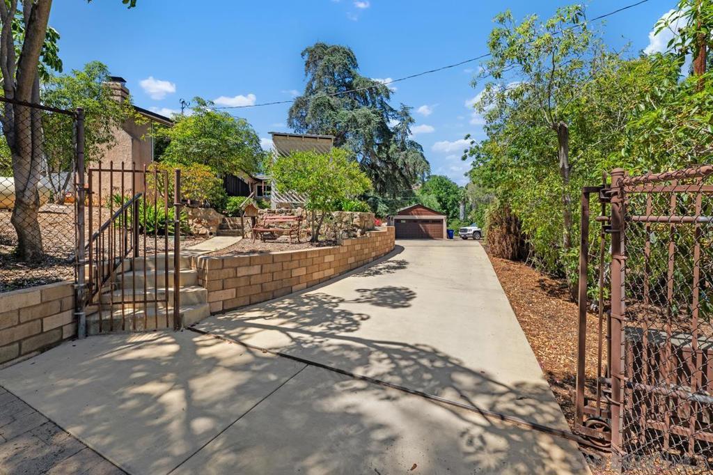 First time on the market since 1966, this Mt. Helix property is on nearly an acre of land, fenced and gated for privacy. Built in 1936 by Abbott & Huston, the 2,023 sq ft. home offers 3 bedrooms—each with walk-in closets—2 baths, and a full basement with separate entrance and bath which could be used as a hobby area, playroom, or even a rental or in-law suite. The remodeled primary bath features marble counters, dual-head walk-in shower, and soaking tub. An updated kitchen with skylight, solid wood cabinetry, and eat-in island, flows into the great room with vaulted ceilings, rock fireplace, a view deck, and access to a enclosed patio. The property’s award worthy mature landscape is a private garden paradise featuring numerous varieties of fruit trees, an amazing “rain tree”, majestic staghorn ferns, and unique specimen trees such as the giant rubber tree, loved by both nesting hawks and flocks of wild parrots. Along with a tea house, custom potting area, barn/tack room, and detached 2-car garage, the property has ample parking to accommodate RVs, trailers, and toys. Recent upgrades—new roof, owned solar with battery backup, upgraded electrical, refinished oak flooring, new sewer line, and updated fixtures—add peace of mind. Zoned for animals, the property embraces Vista de la Cruz’s agrarian lifestyle.
