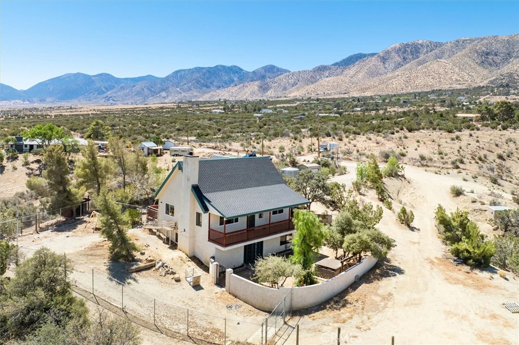 Nestled on a serene hillside in Juniper Hills sits a tri level home offering expansive mountain and desert views. Set on a sprawling 3 acre lot the property blends privacy and peacefulness with panoramic beauty. The home features 4 bedrooms and 3 baths in approximately 2100 sq. ft.. Thoughtfully laid out to provide both functionality and comfort. The main living level boasts an open concept design. The kitchen is the heart of the home open to the living room with a cozy fireplace and access to the back deck for stargazing! 2 bedrooms and a full bath round out the main floor. Upstairs features a main suite with a private 4 piece bath. On the lower level you'll find a versatile space ideal for a guest suite, home office or media room, along with a 3rd bath. Additionally it includes laundry facilities and access to the backyard. The expansive acreage offers endless possibilities and simply enjoy the quiet natural surroundings.