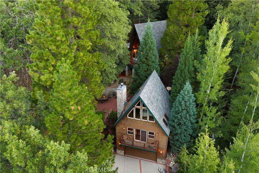 Two iconic A-frames on one property, nestled just off the waters of coveted North Bay. A seasonal creek winds between the cabins, with a treehouse tucked out back, creating a setting that feels private yet keeps you close to everything the lake has to offer. This first tier home comes with the ultimate lake package: a multiple dock slip (end slip), boat, and rare level access straight to the water. No endless stairs, just an easy walk to the dock. Step inside the main house and you’re in a true mountain lodge. Rustic wood paneling, walls of glass, exposed beams, and stone accents bring the outdoors in. The home offers 3 bedrooms, 2 baths, decks on both sides, and a jacuzzi with a peek of the lake, perfect for tranquil evenings. Follow the stairs down through the expansive outdoor patio to the guest A-frame, where you’ll find 1 bedroom, 1 bath, a cozy living space, and a two-car garage underneath for convenience. With wood paneling, large windows, a small deck off the living room, and a loft-style bedroom, it carries the same rustic charm. Outdoors, a spacious patio and outdoor kitchen set the scene for entertaining or simply slowing down and taking in the mountain air under the trees. Iconic architecture. Rare lake access. A lifestyle package that doesn’t come along often. This is Lake Arrowhead at its best.