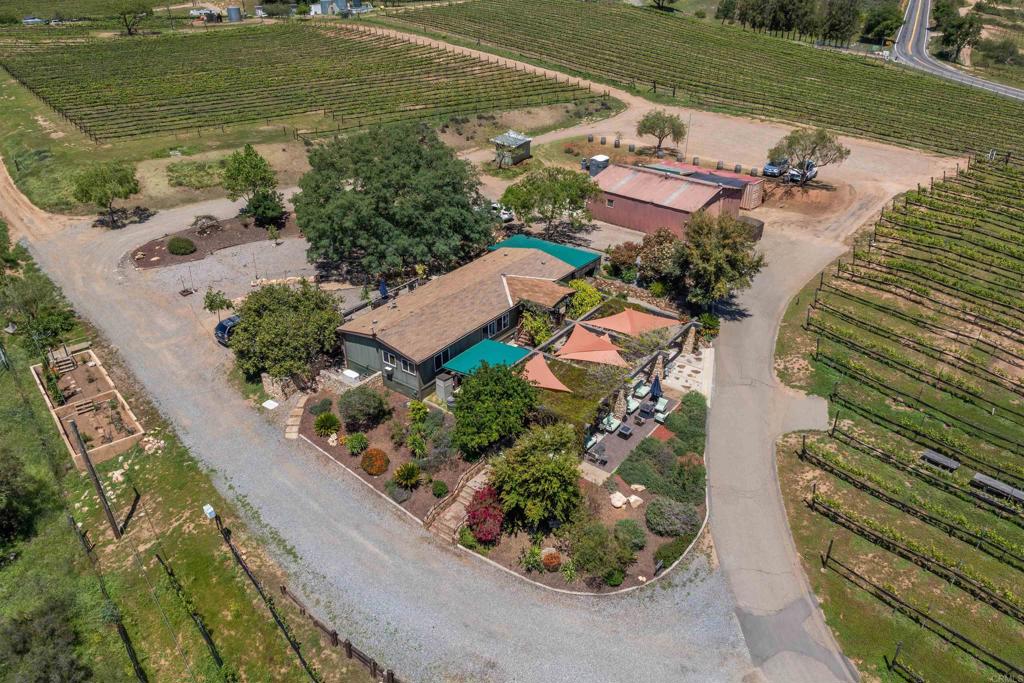 Nestled in the picturesque valley of Old Julian Highway in the thriving Ramona community, award-winning Vineyard GrantJames offers a unique opportunity to own a piece of California’s flourishing wine country. Spanning nearly 9 acres, this established winery has been operating since 2009 and is fully equipped for continued success in the growing Ramona Valley wine scene. The property includes a beautifully appointed 3-bedroom, 2-bath manufactured home with a spacious back deck, where you can soak in breathtaking views of majestic oaks and rolling vineyards. A 40x30 metal barn serves as the winemaking hub, featuring a fully equipped lab, ample storage, and self-sufficient amenities like a private well and an automated backup generator. Guests will love the meticulously landscaped wine-tasting patio, complete with a bubbling fountain, perfect for enjoying the serene surroundings. With ample parking and plenty of charm, this property offers the rare chance to live, work, and thrive in one stunning location.